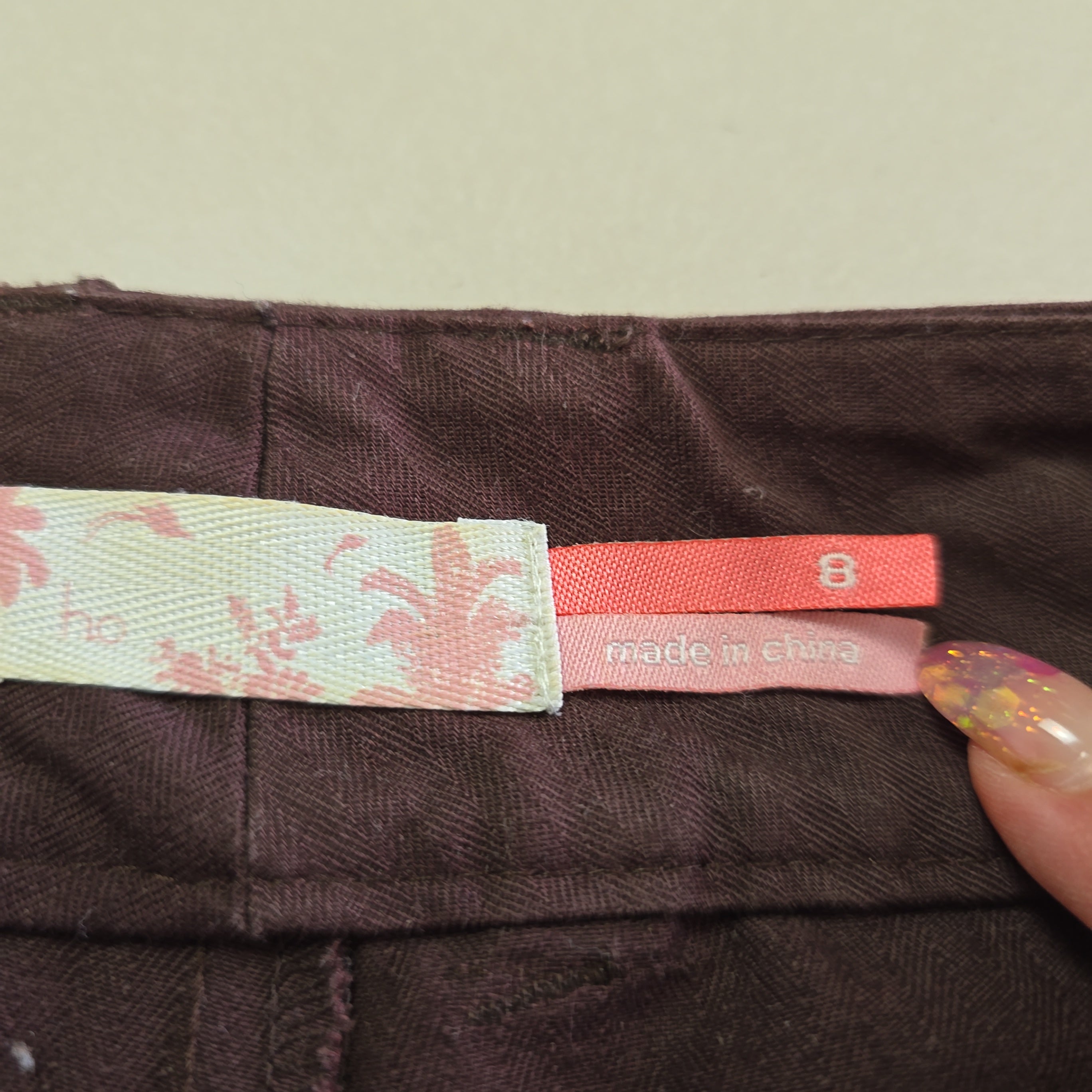Close-up of a brown textured fabric with a floral-patterned tag and red label.