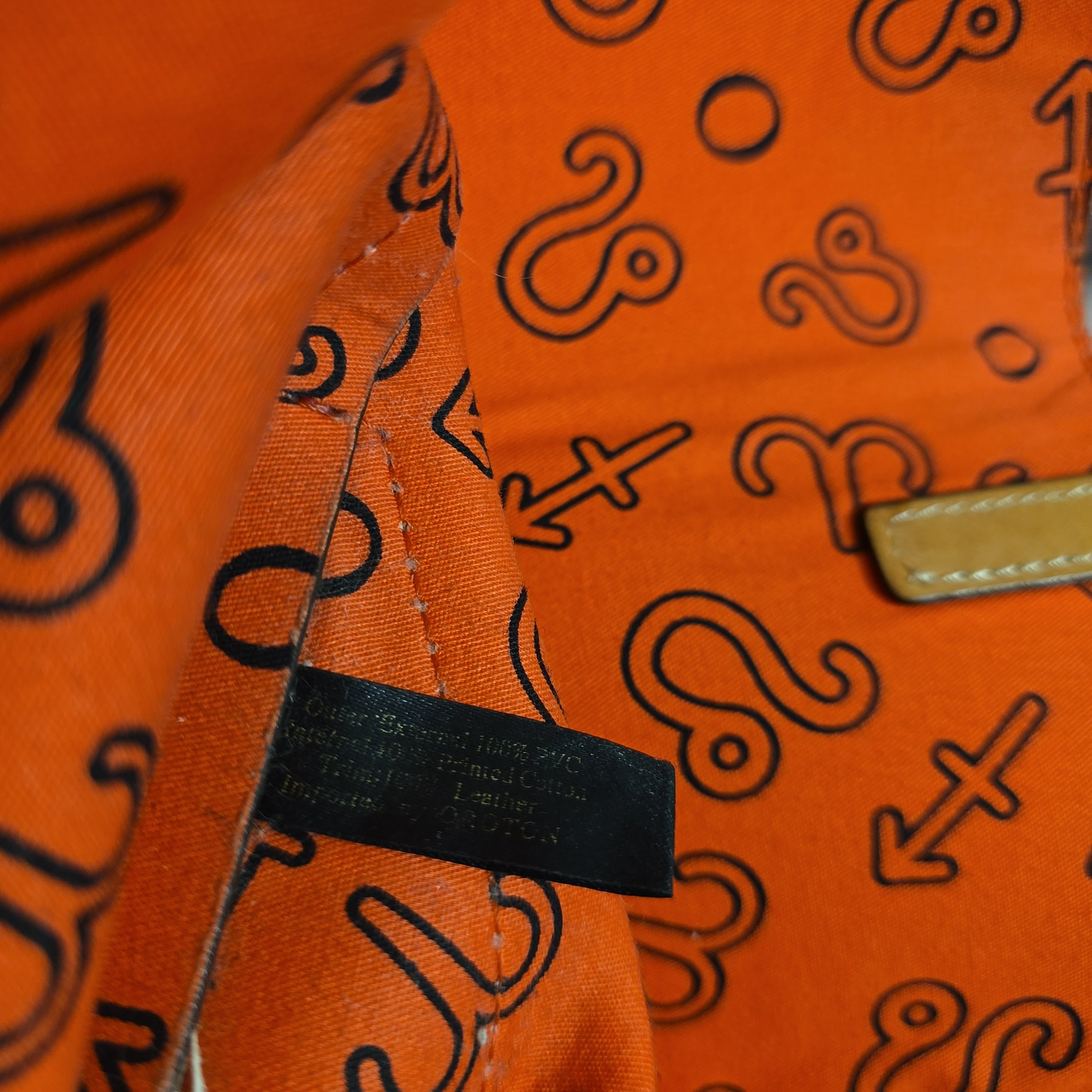 Close-up of an orange bag with black patterns and a visible brand tag.