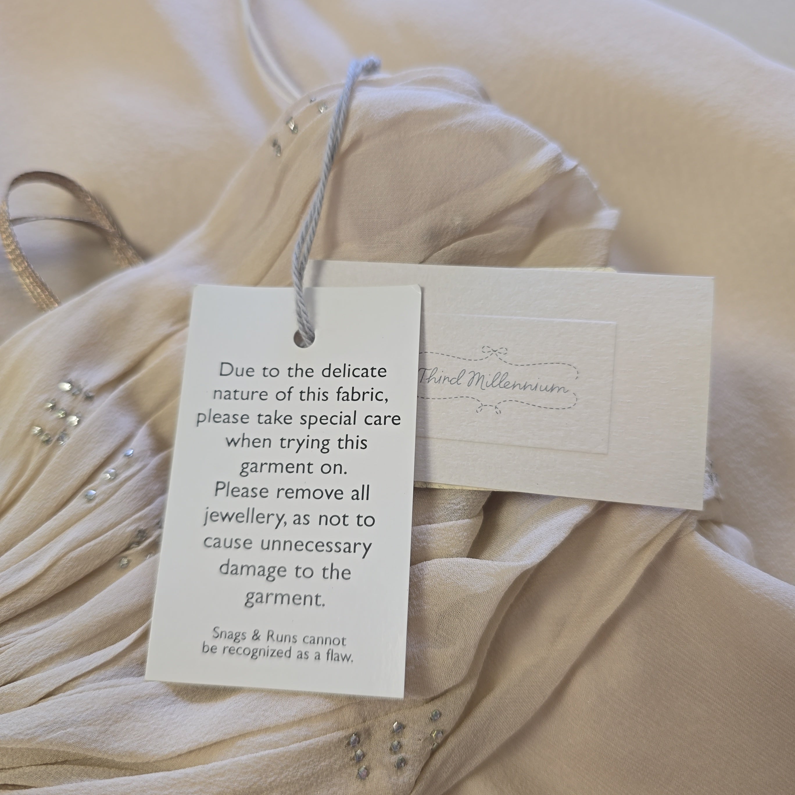 Fabric with care tag and warning label on a beige fabric background
