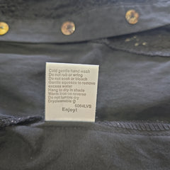 Label on a dark top with text and a brand logo.