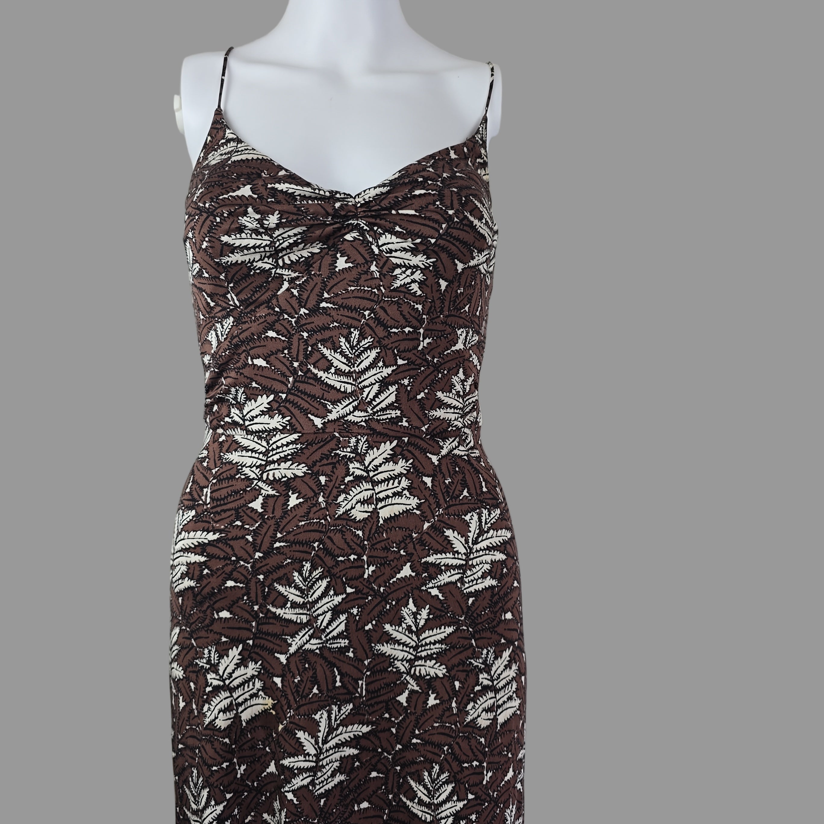 Mannequin wearing a brown and white patterned dress on a plain background