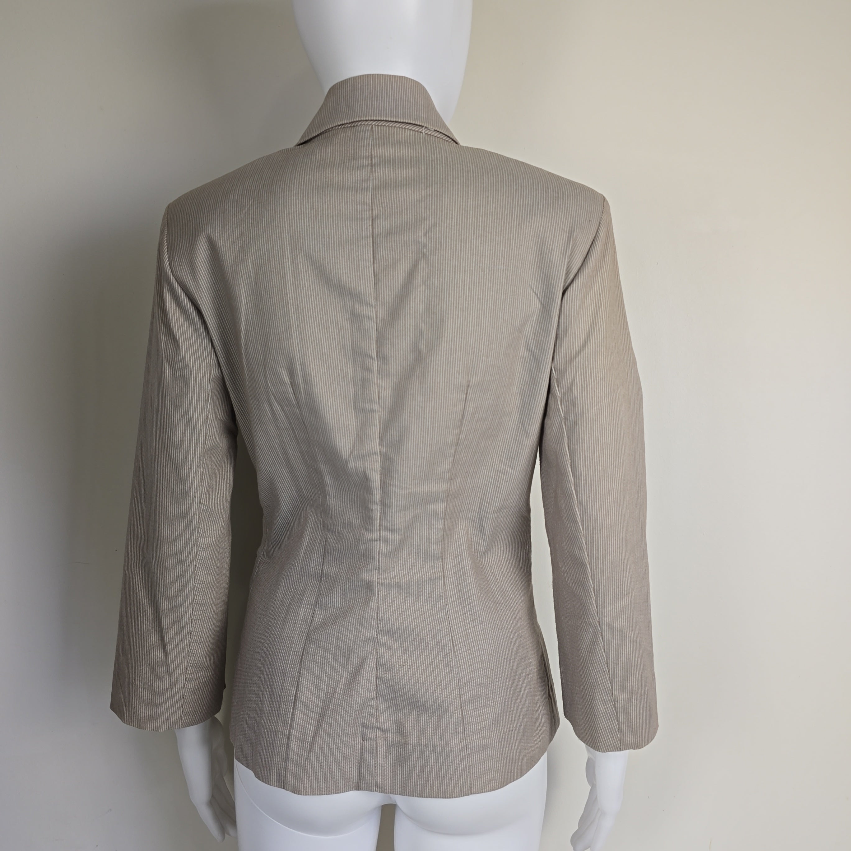 Beige jacket on a mannequin against a plain background