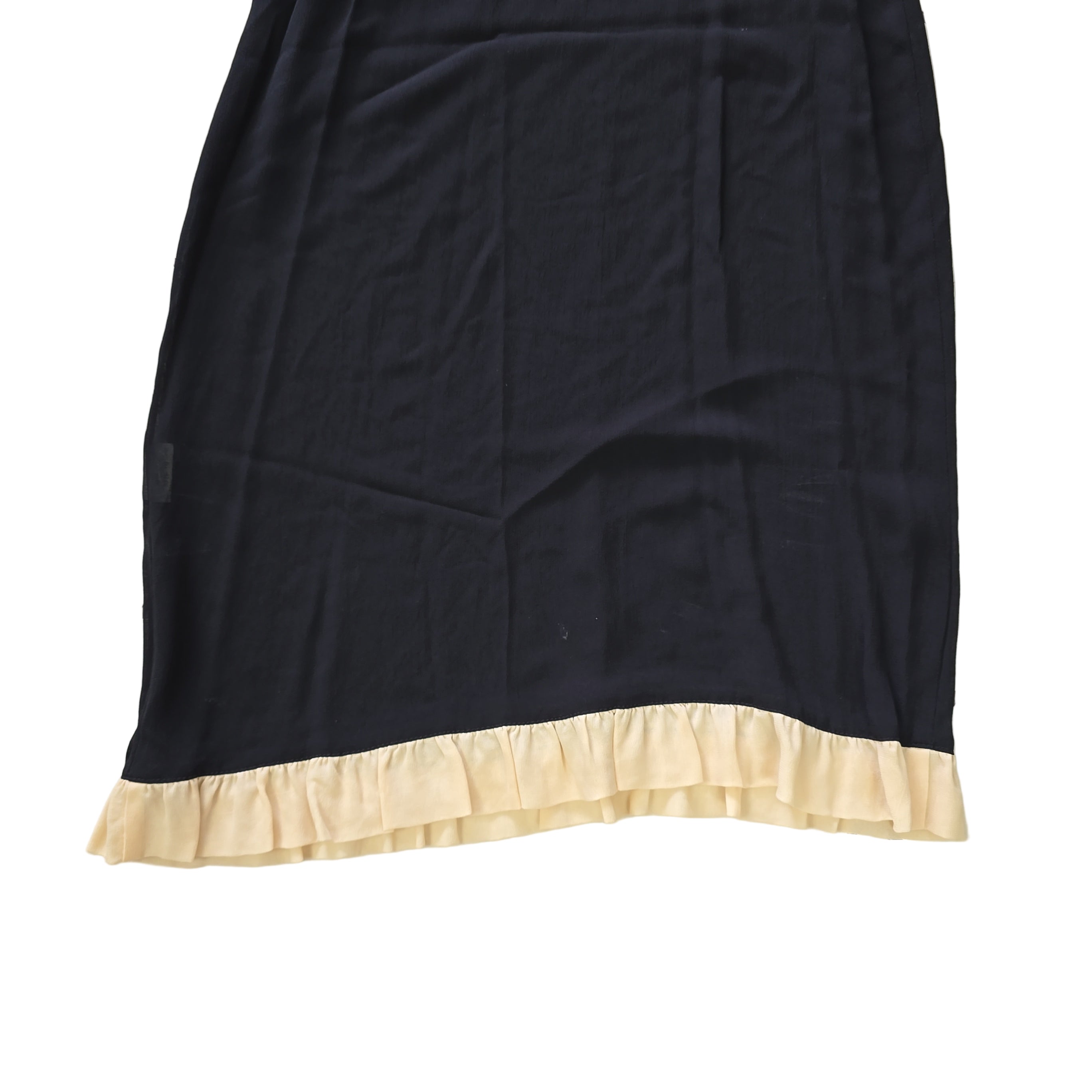 Black fabric with beige ruffled edge on a tiled floor