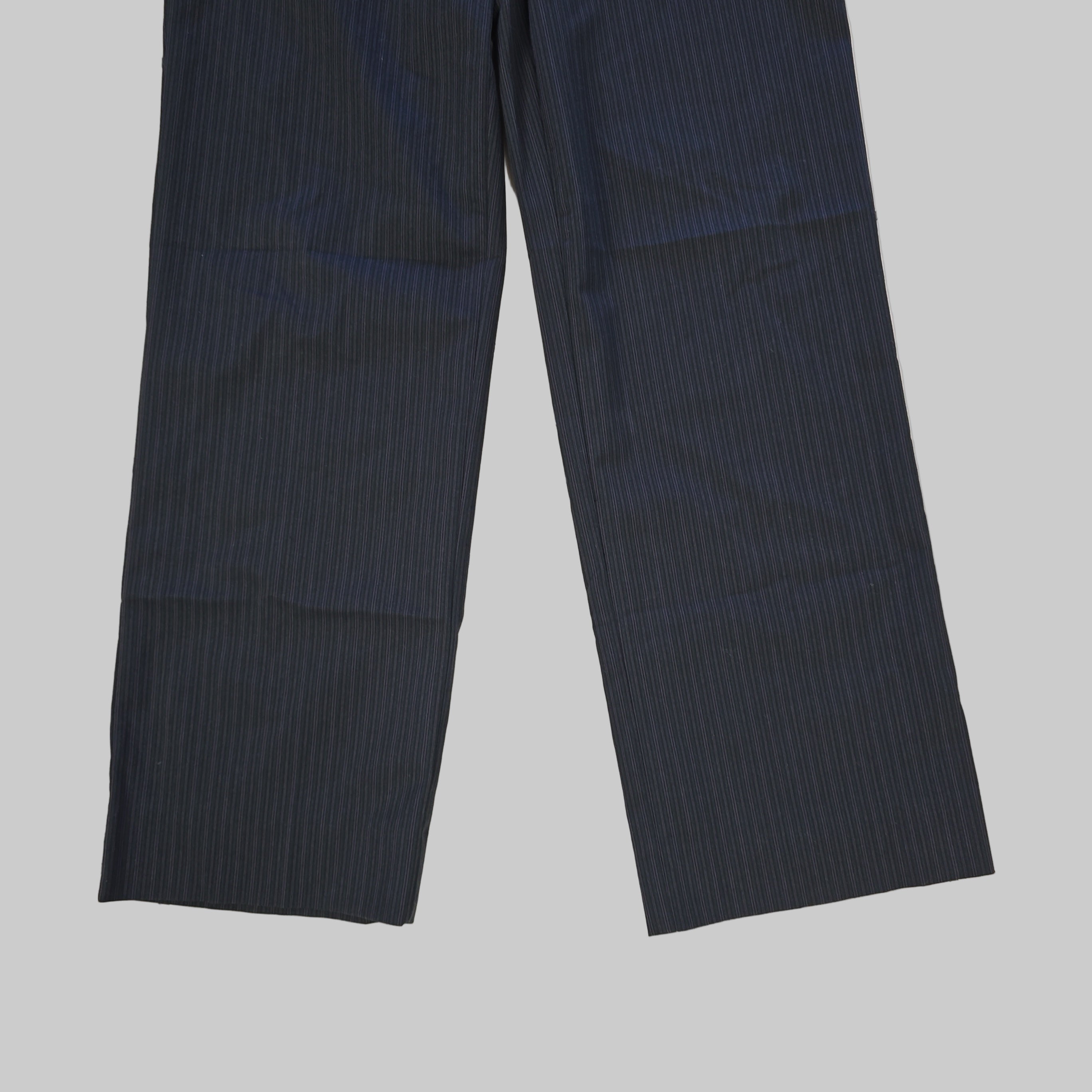 Two grey striped pant legs fabric on a tiled floor