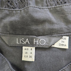 Gray top with 'Lisa Ho' branding and size tags on a close-up of the fabric.