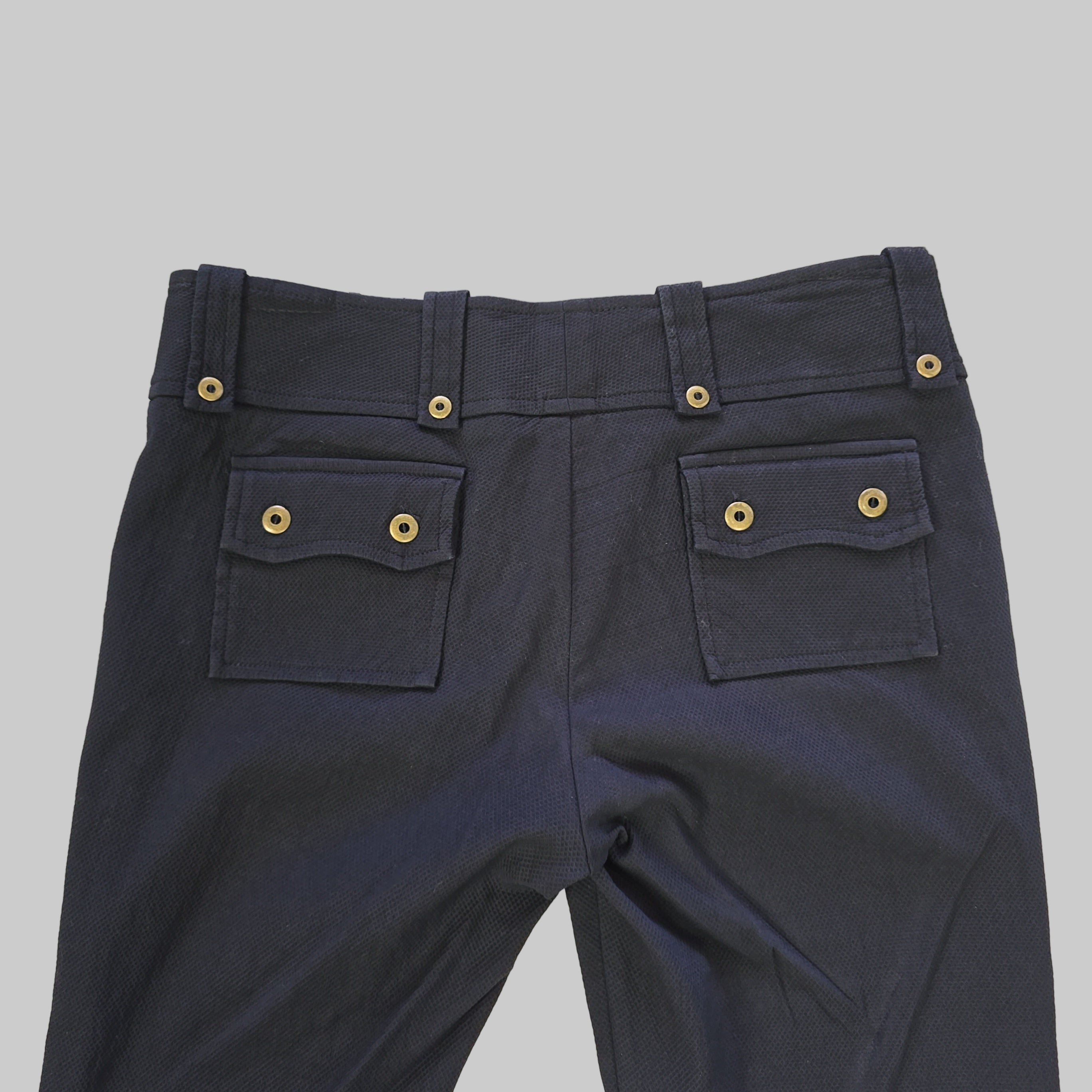 Black pants with gold buttons on a tiled floor