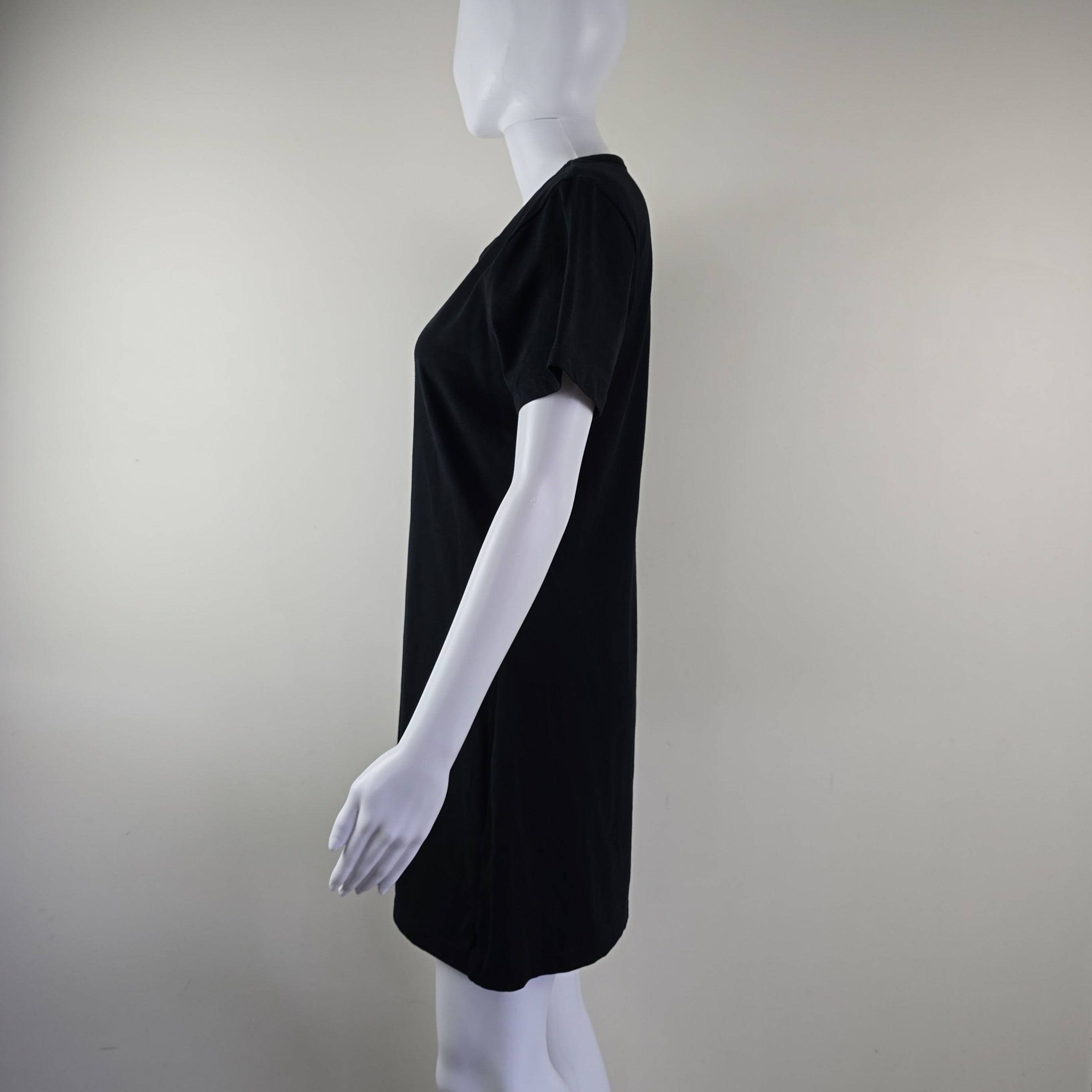 Black dress on a white mannequin against a plain background