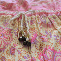 Close-up of a pink and purple patterned fabric with a string and decorative elements.