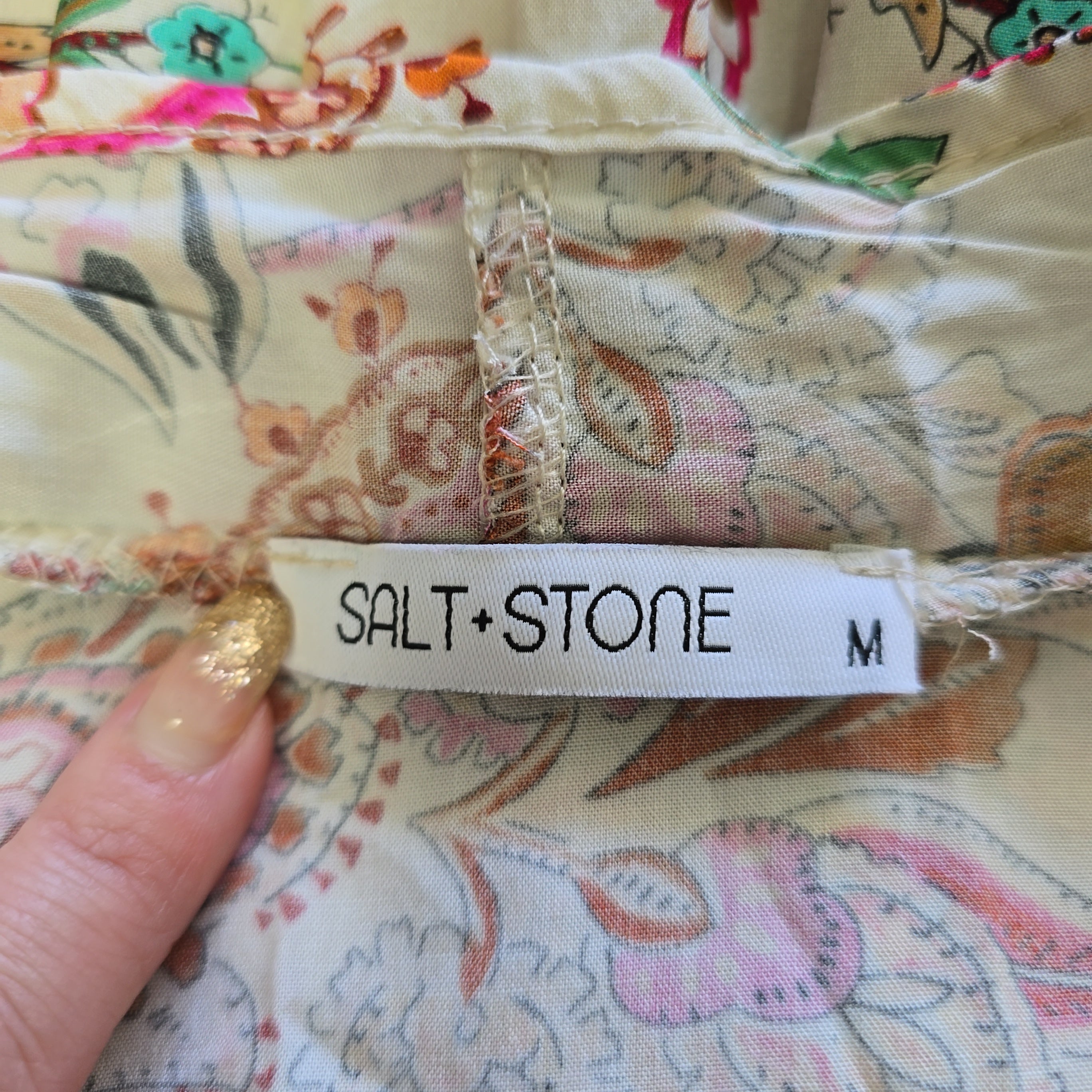 Close-up of a 'Salt + Stone' tag on floral fabric.