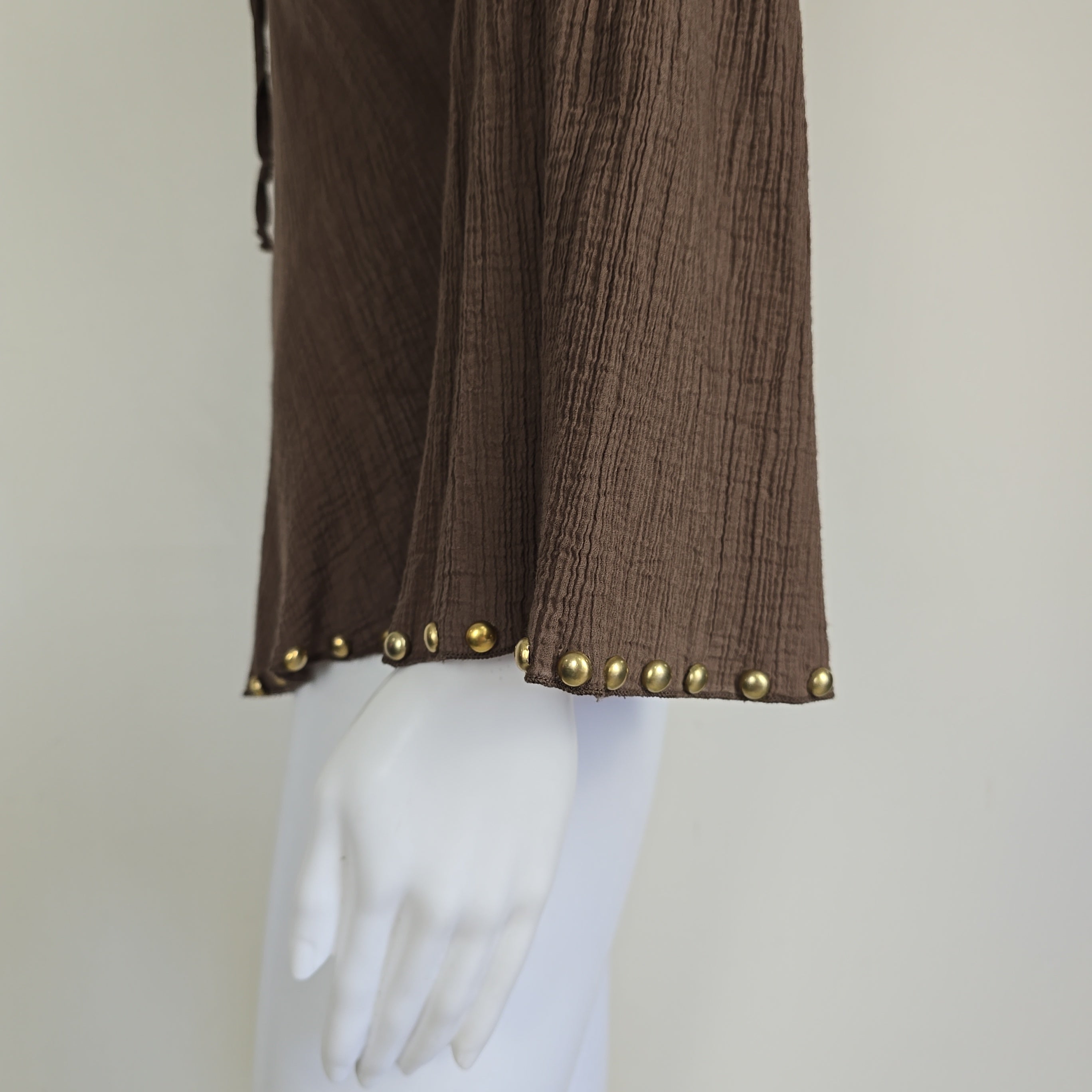 Brown fabric with gold studs on a white mannequin against a beige background