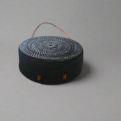 Black woven basket with orange accents on a tiled floor