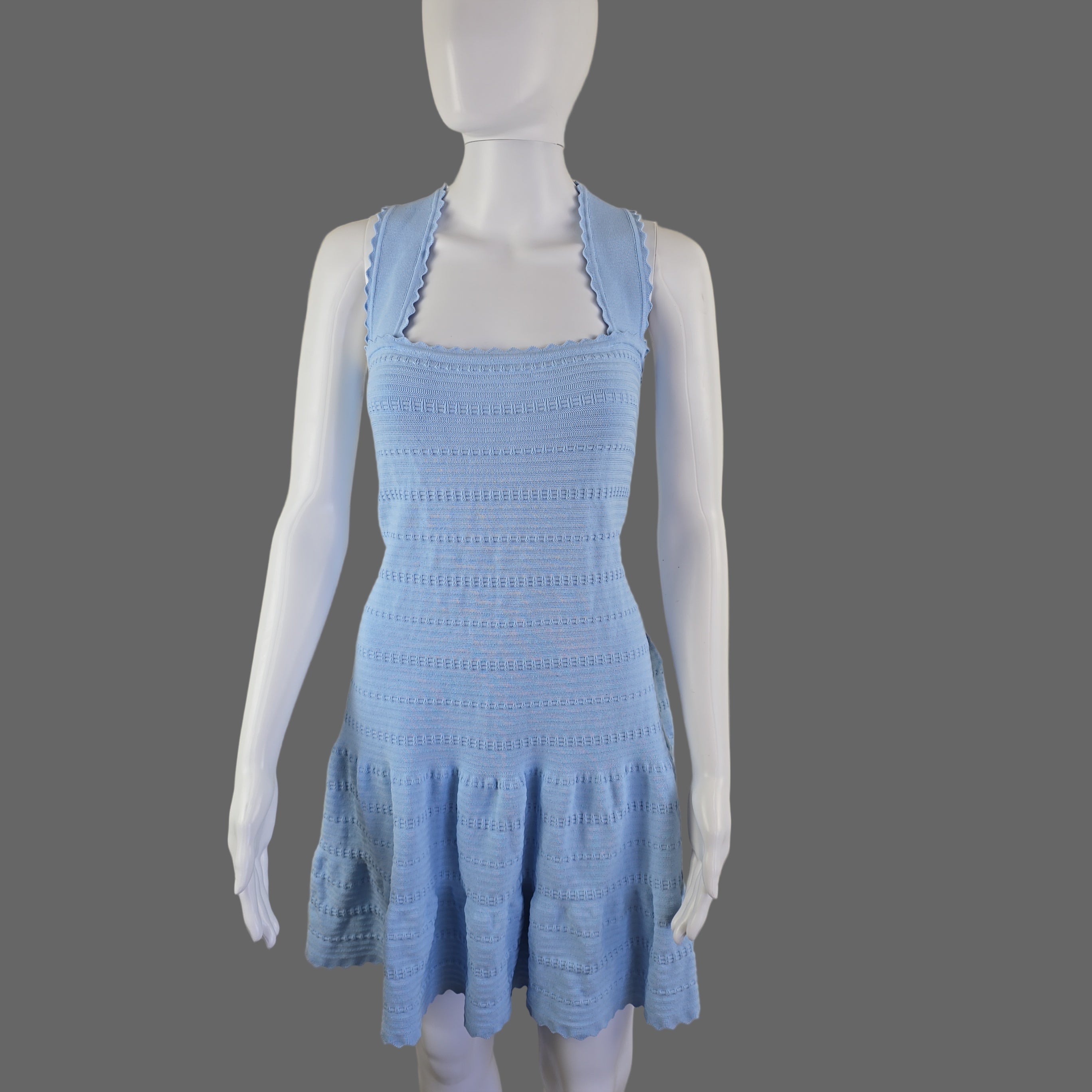 Blue dress on a mannequin arm against a plain background