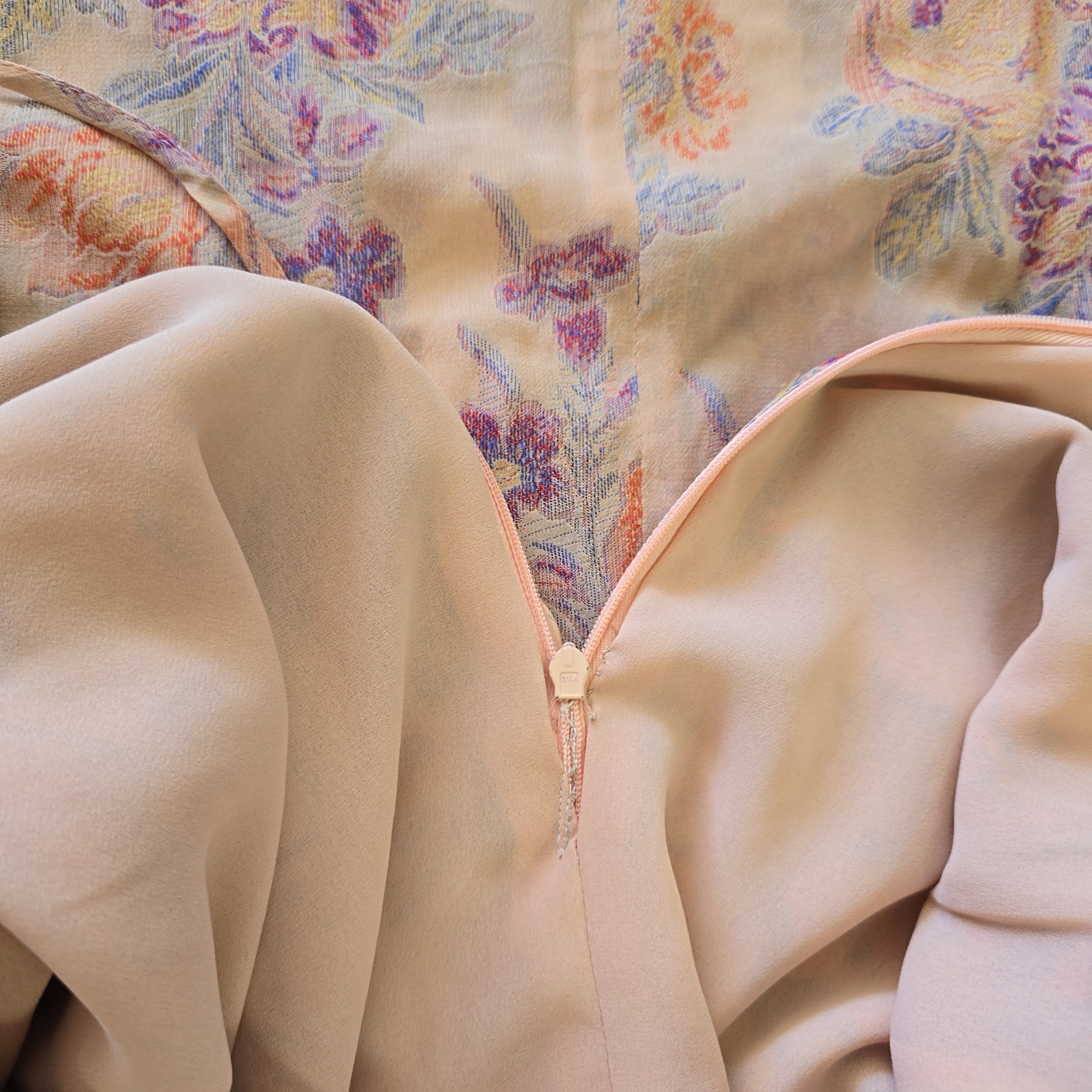 Close-up of beige fabric with floral patterned fabric in the background