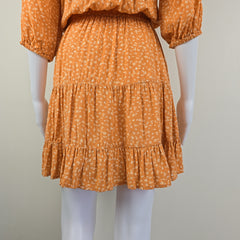 Orange dress with ruffled details on a mannequin against a neutral background