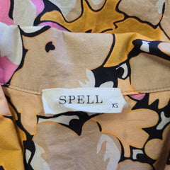 Close-up of a fabric with abstract patterns and a 'SPELL' label on a beige background.