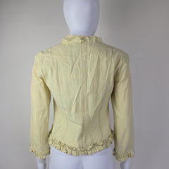 Light yellow jacket with frill details on a light background