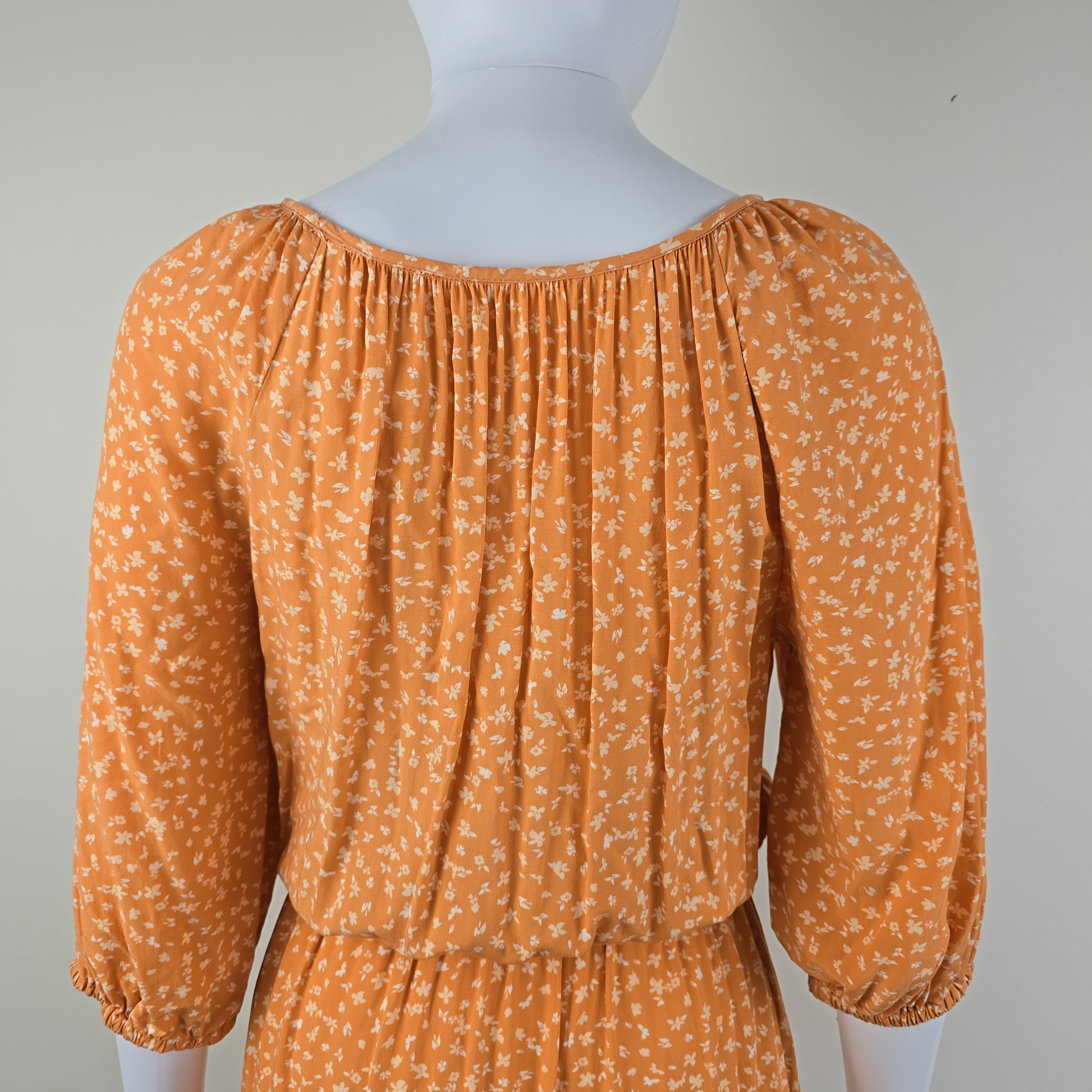 Orange floral dress on a mannequin against a white background