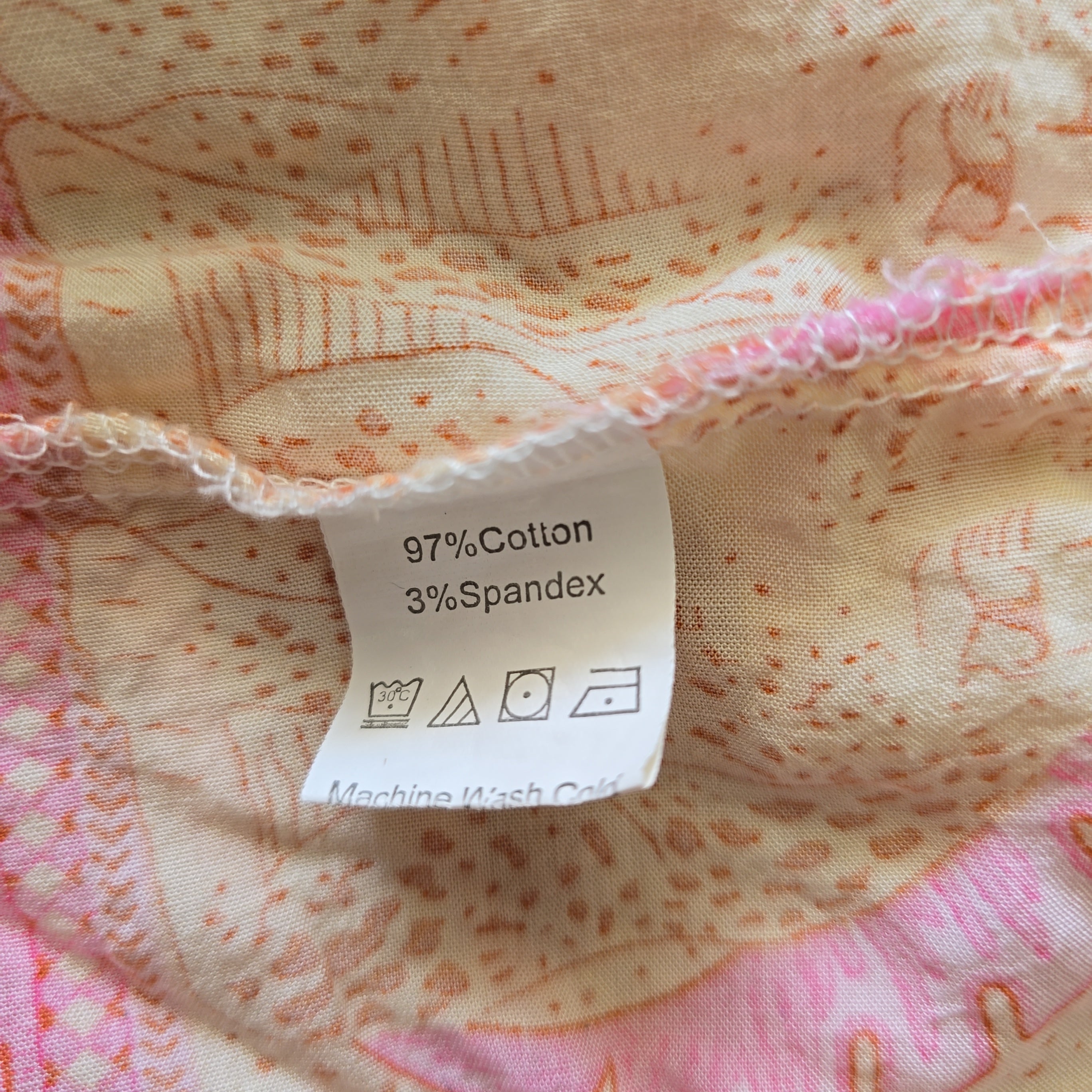 Fabric with a label showing 97% Cotton and 3% Spandex on a pink and orange patterned background.