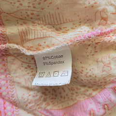 Fabric with a label showing 97% Cotton and 3% Spandex on a pink and orange patterned background.