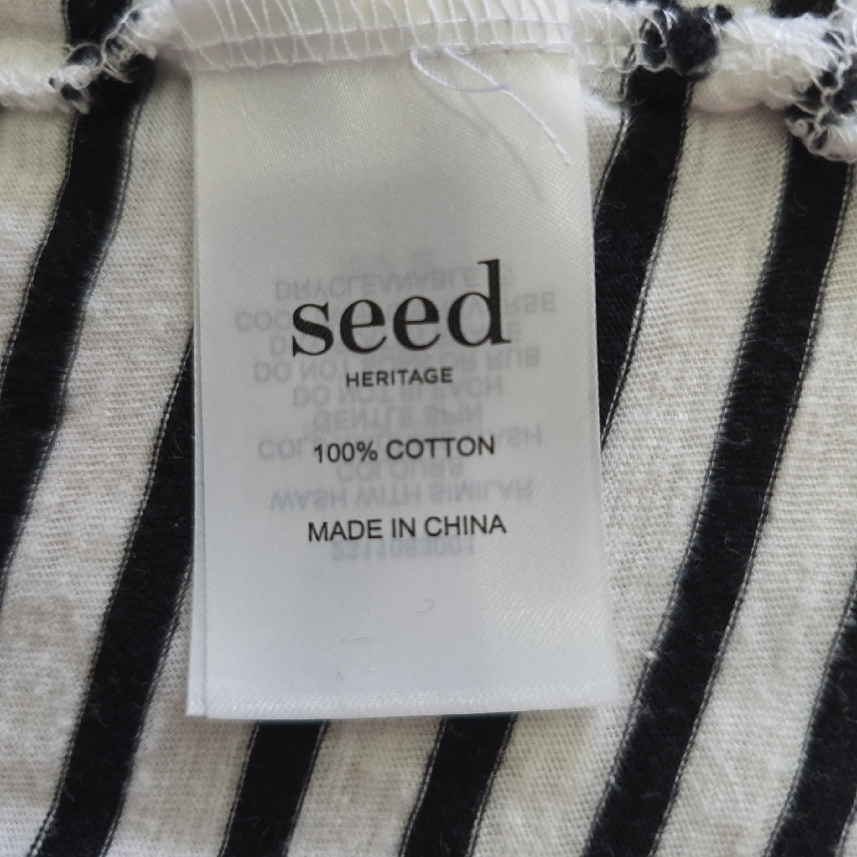 Seed Heritage label on a black and white striped fabric background