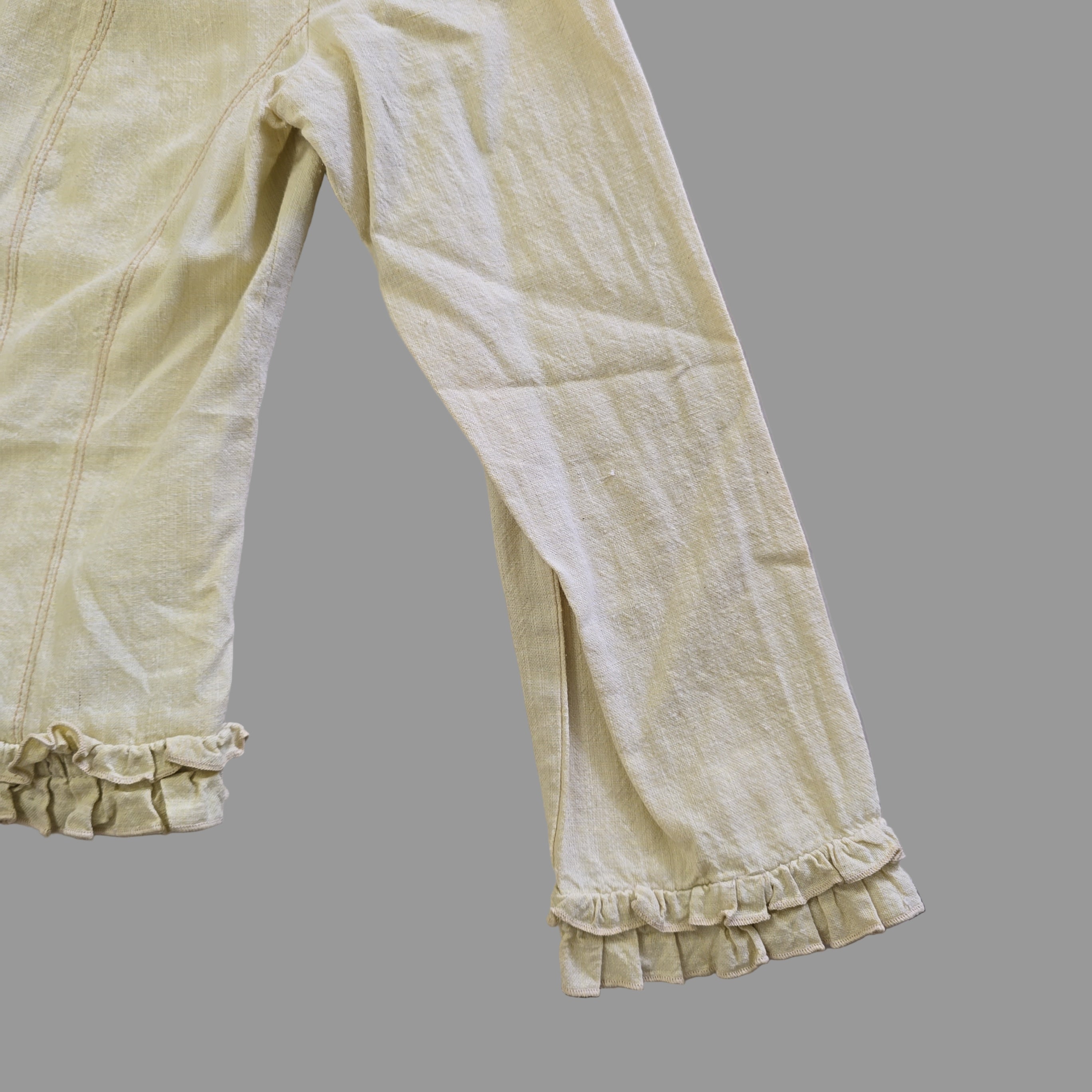 Light yellow jacket with frill details on a light background