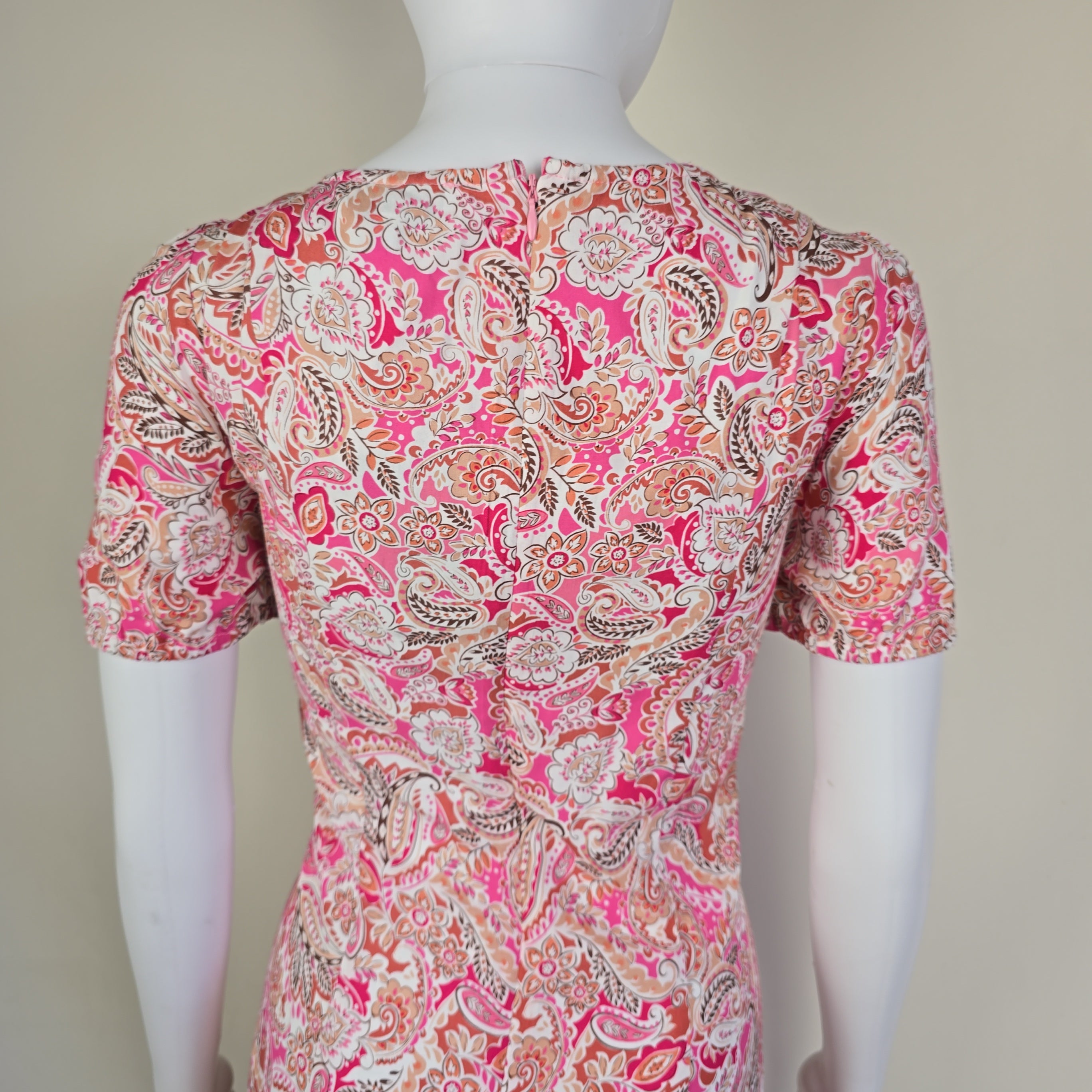Mannequin wearing a pink paisley dress with a neutral background