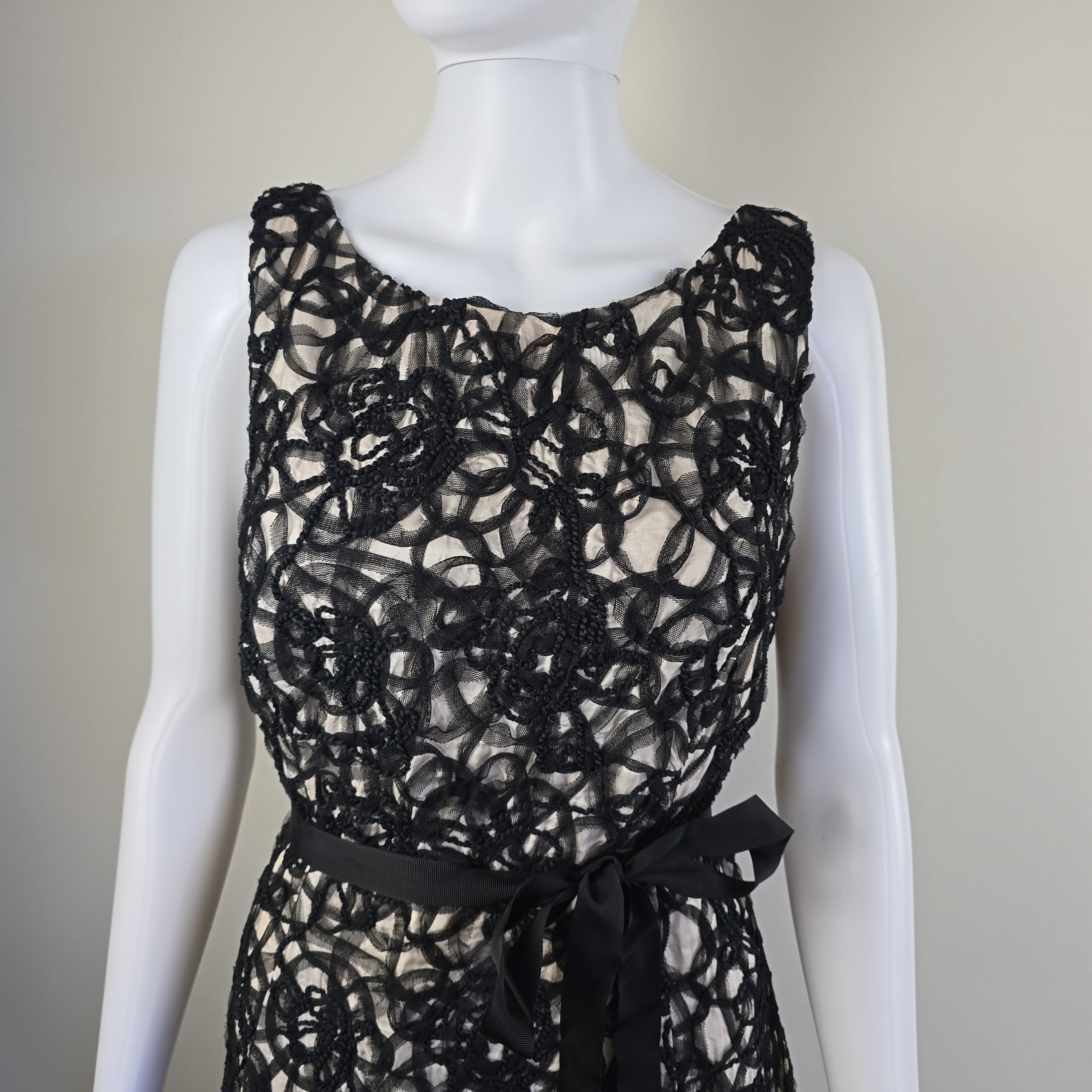 Black lace garment on a mannequin against a neutral background