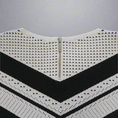 White knitted top with black stripes and a zipper on a beige background