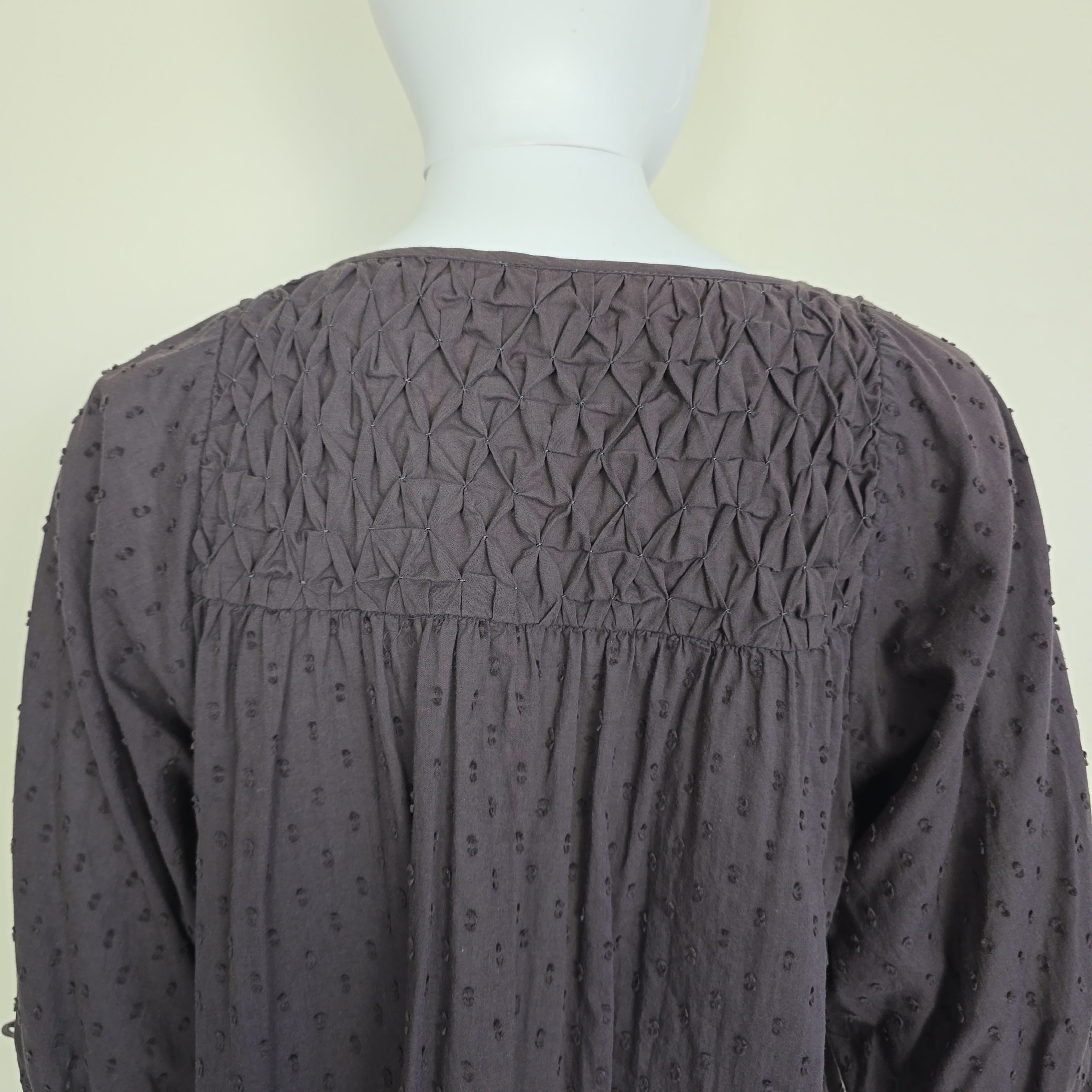 Dark brown textured fabric on a mannequin with a plain background