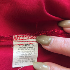 Close-up of a red fabric with a label held by a hand.