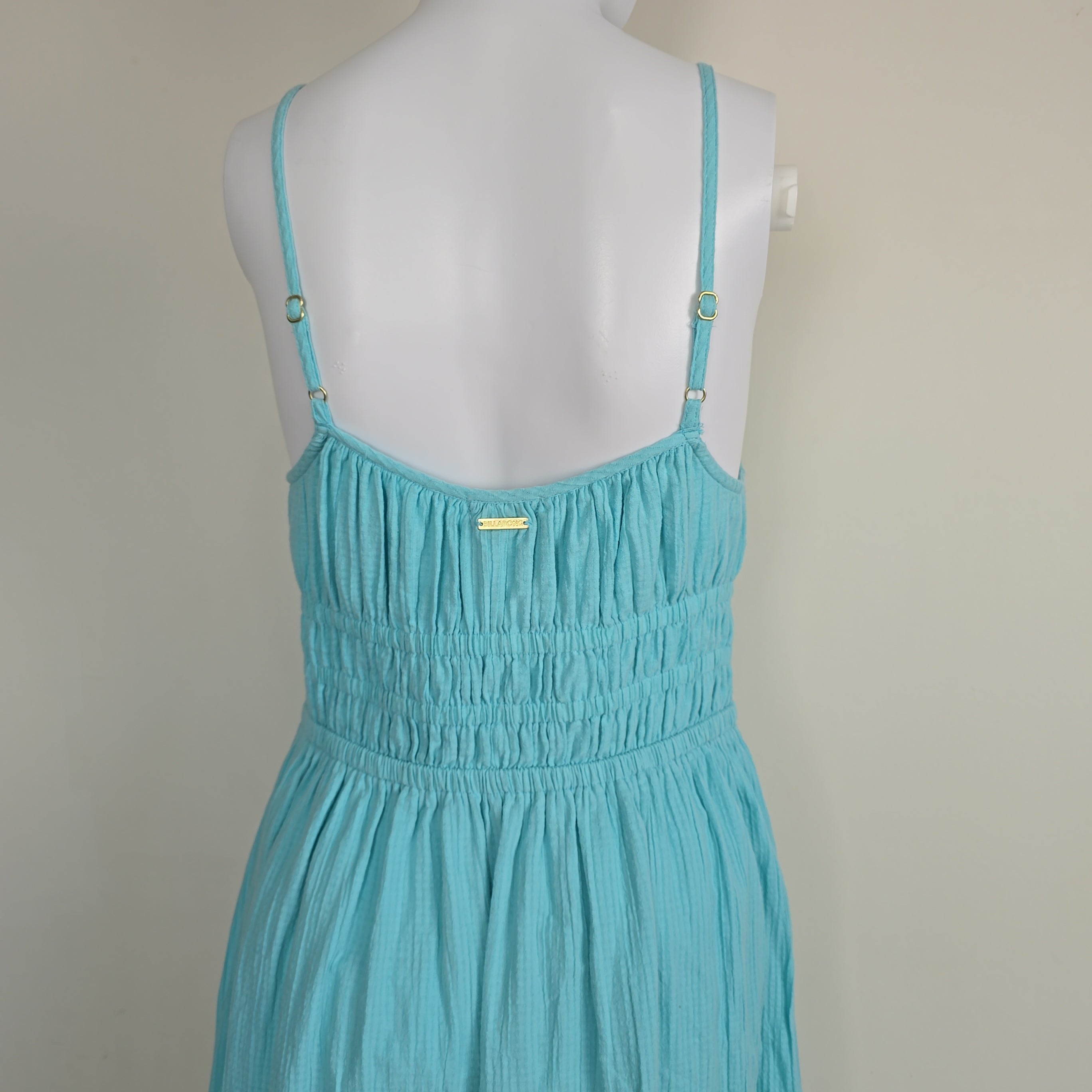 Turquoise dress on a mannequin against a neutral background