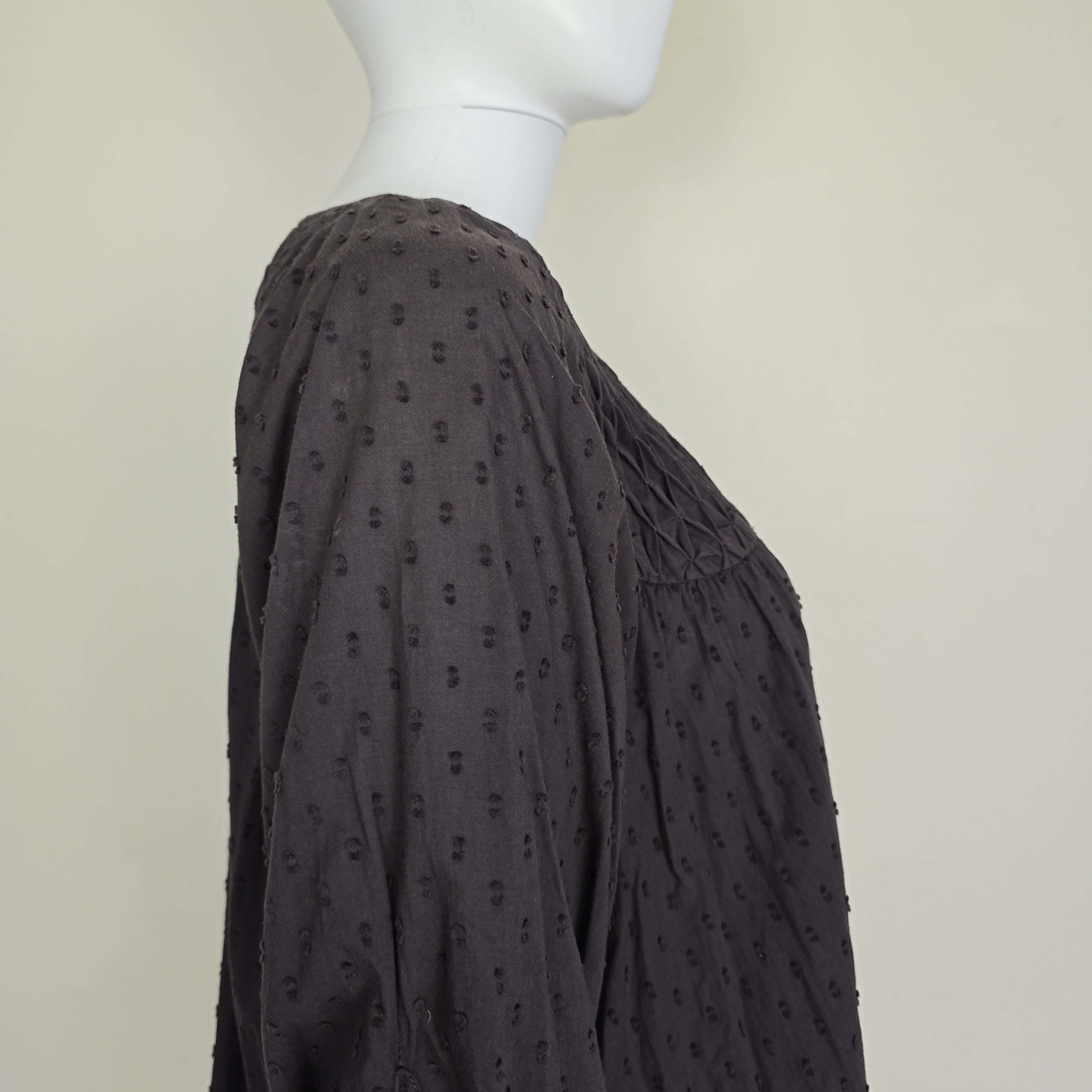 Brown textured fabric on a mannequin against a beige background