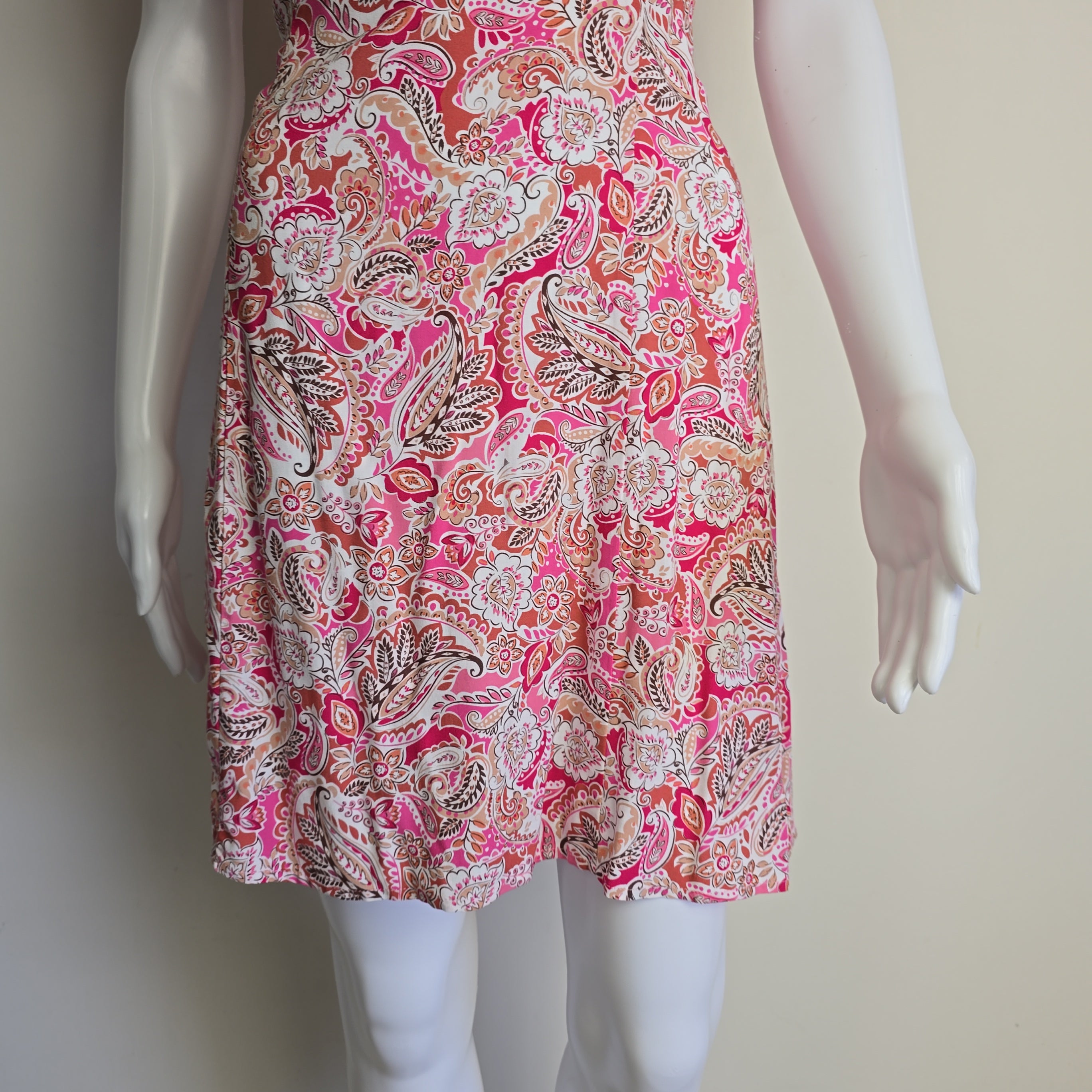 Mannequin wearing a pink paisley dress with a plain background