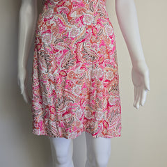 Mannequin wearing a pink paisley dress with a plain background