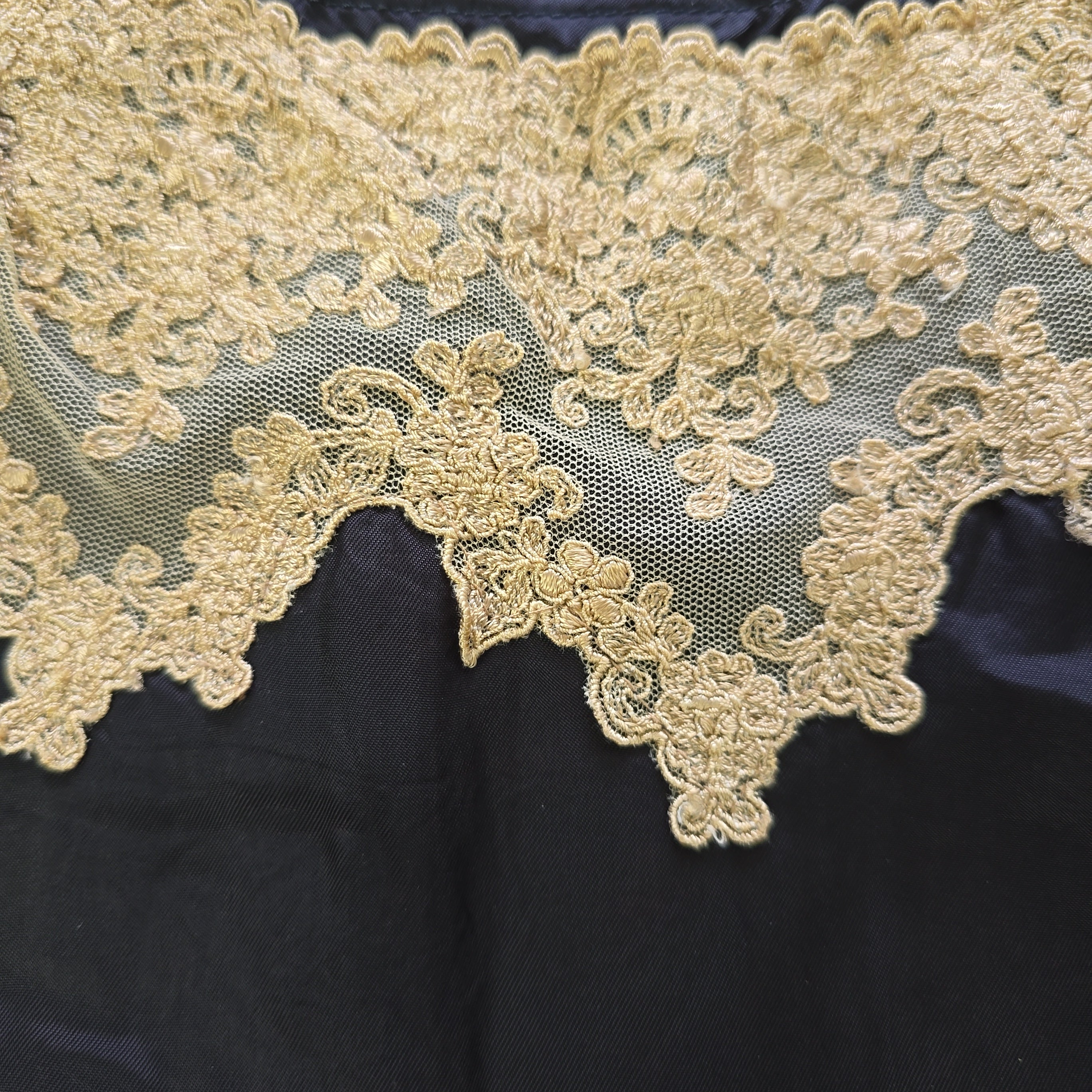 Close-up of gold lace fabric on a dark background