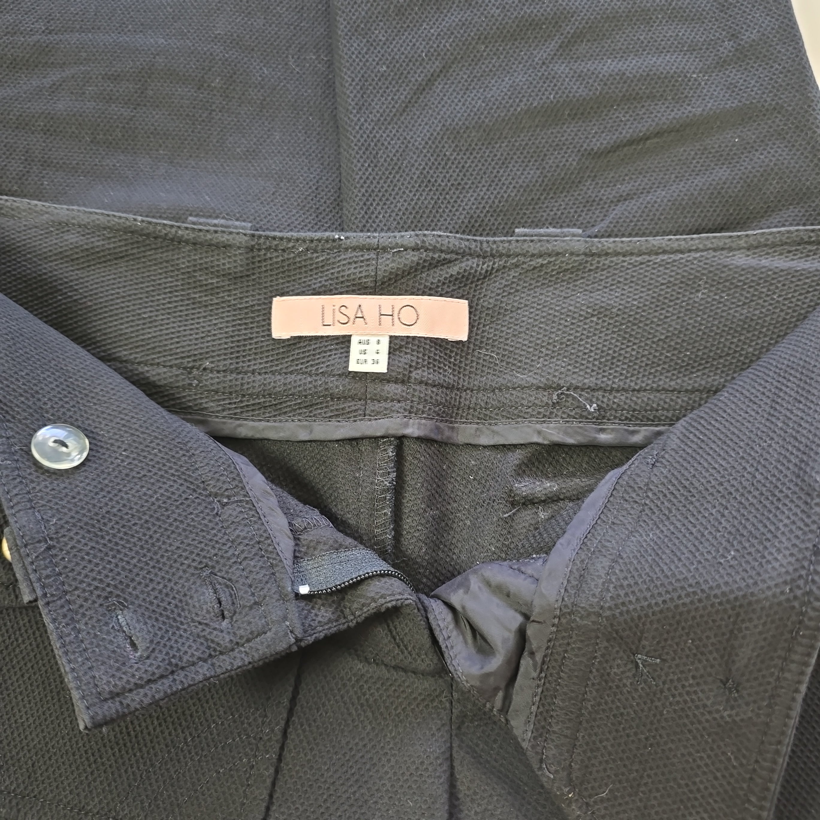 Close-up of a black pants with a visible brand label on a neutral background