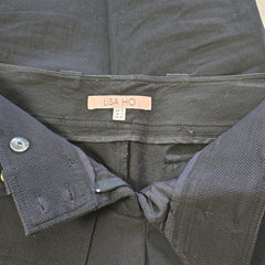 Close-up of a black pants with a visible brand label on a neutral background