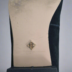 Close-up of a shoe sole with a decorative metal tag on a light background