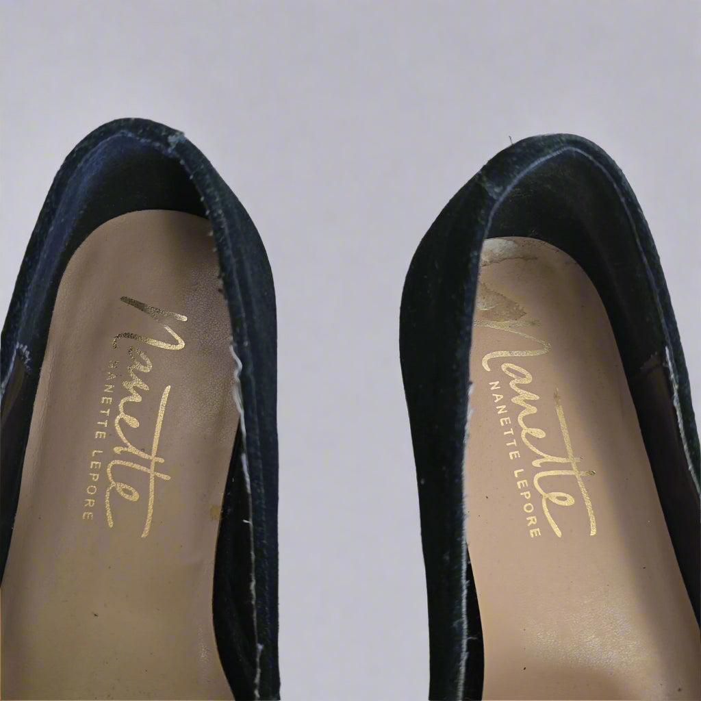 Close-up of black shoes with 'Nanette Lepore' branding on a light background