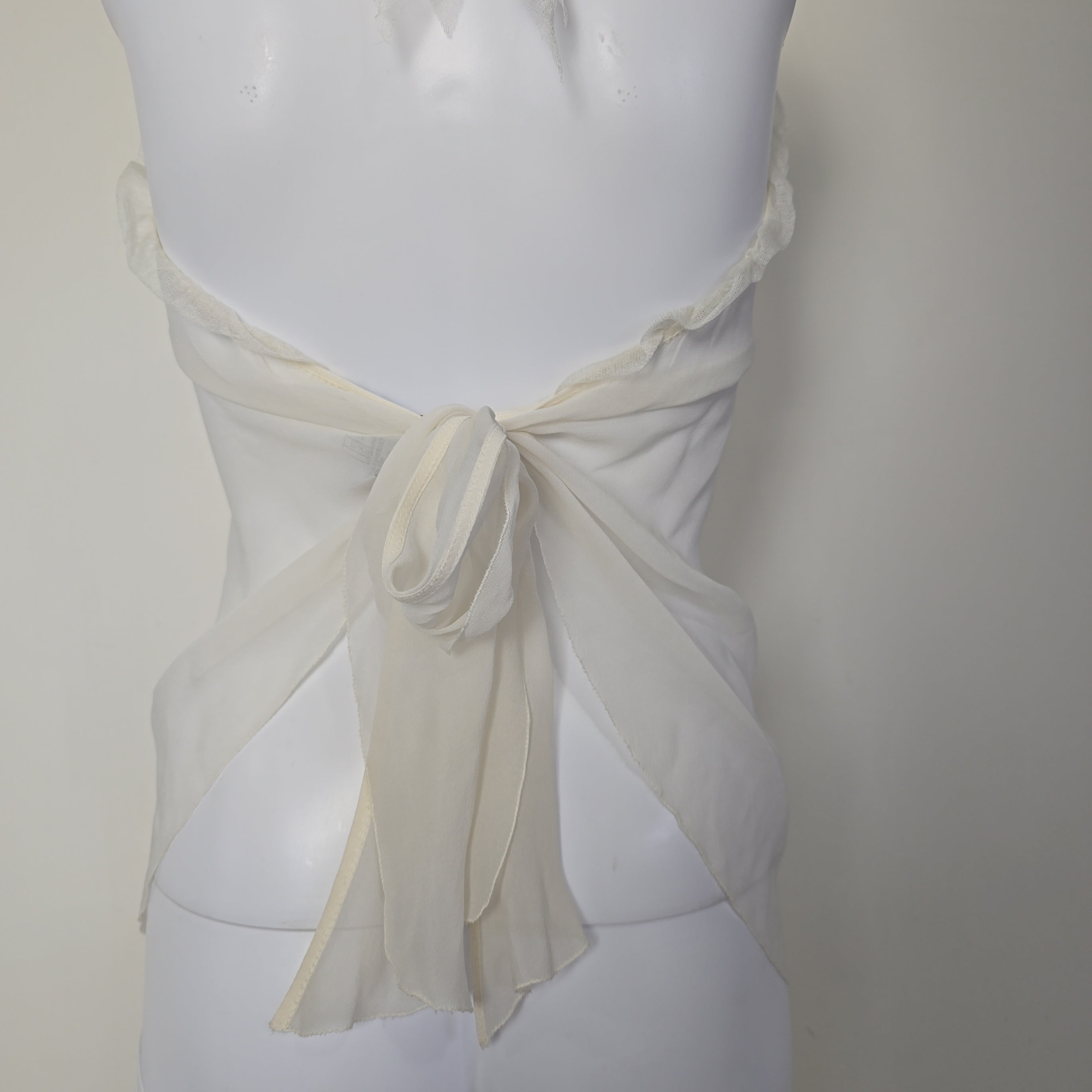 White top with a bow detail on a mannequin against a neutral background