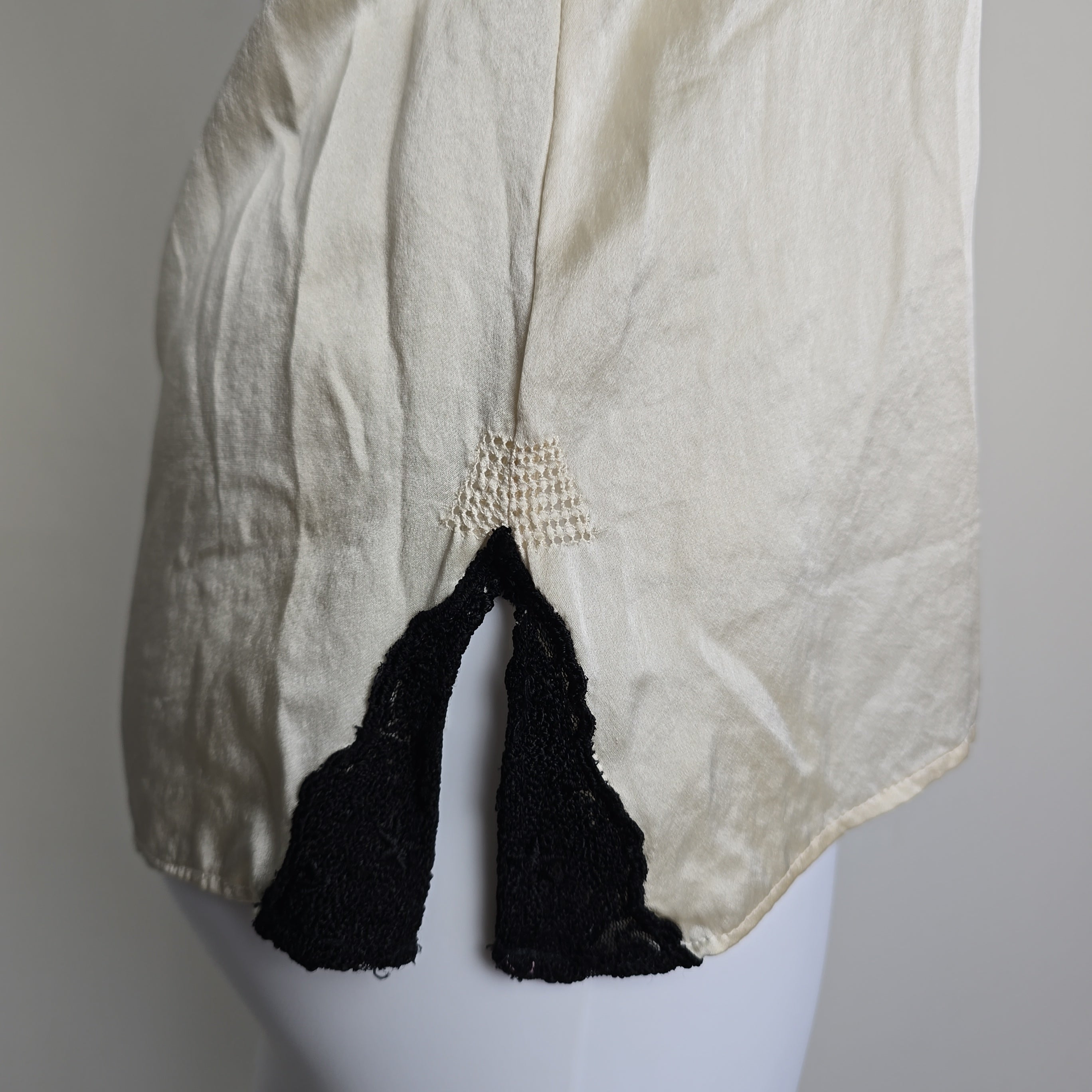 White garment with black lace trim on a white background