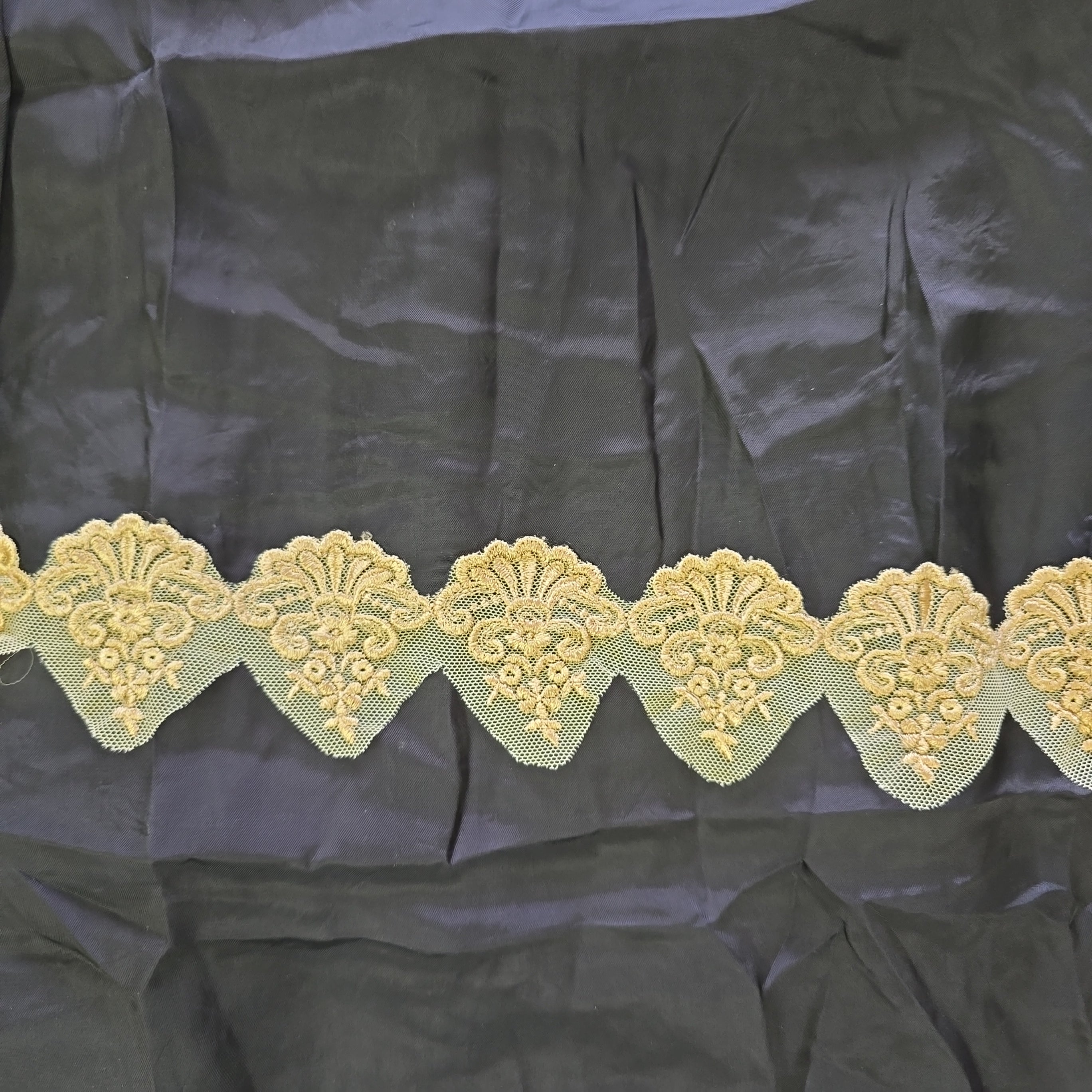 Decorative beige lace trim on a black fabric background