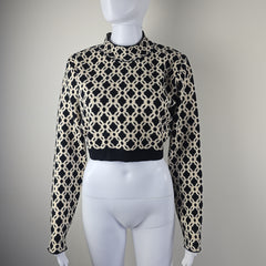 Mannequin wearing a black and beige patterned outfit on a plain background
