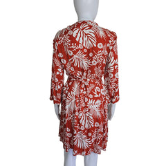 Red and white floral patterned fabric on a mannequin arm against a plain background