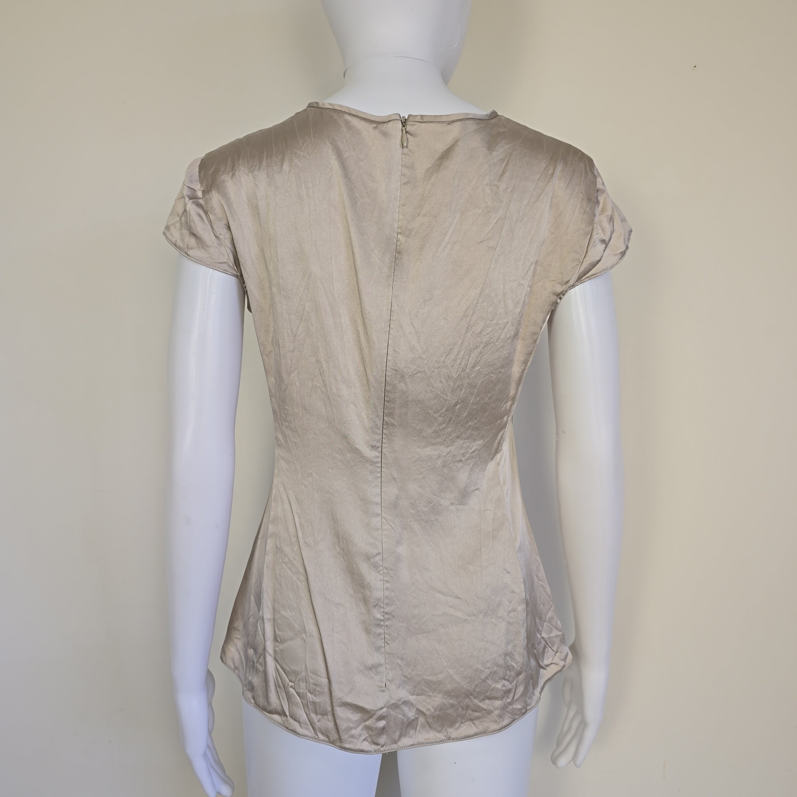 Beige top on a mannequin against a plain background