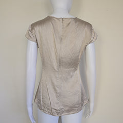 Beige top on a mannequin against a plain background