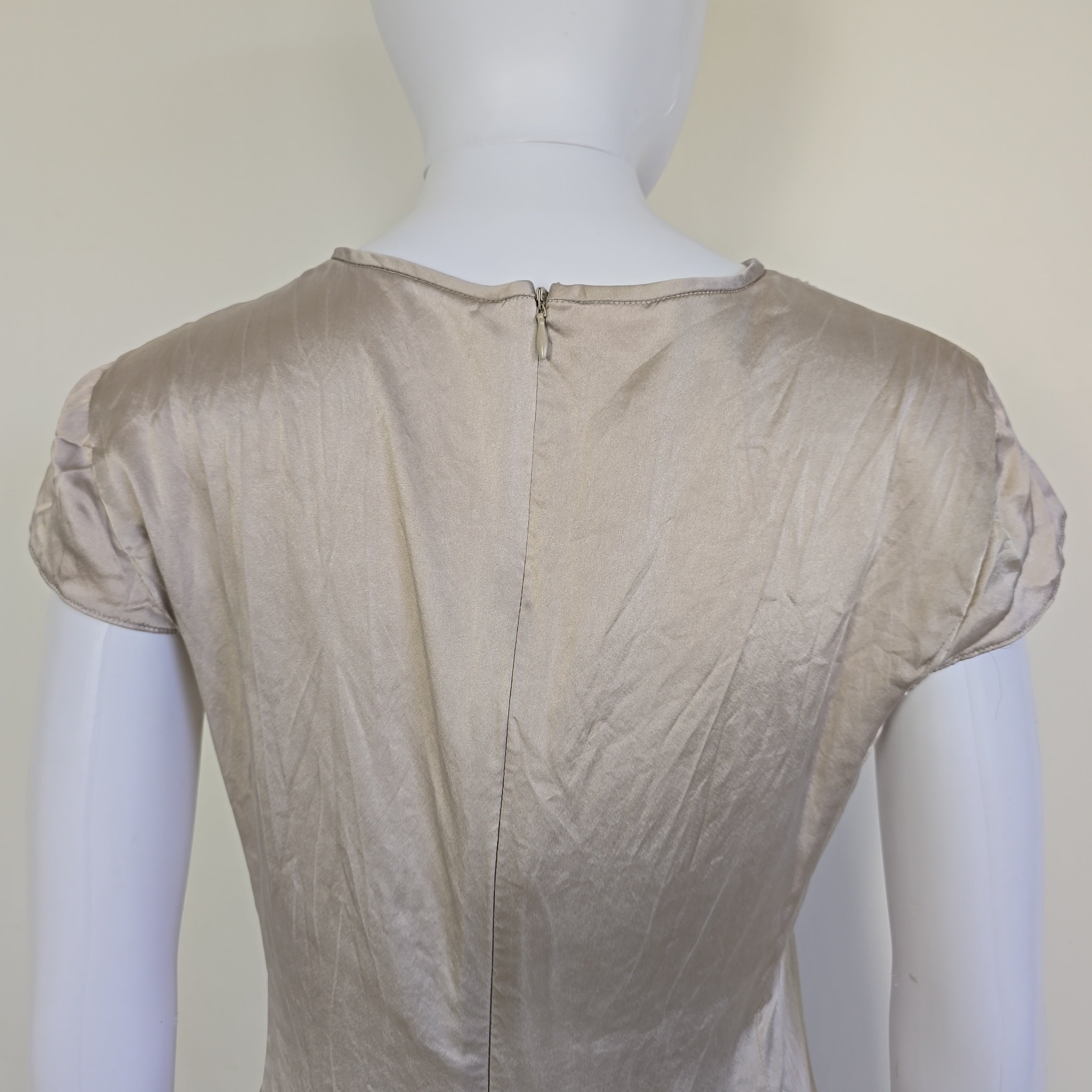 Beige top with a knot detail on alight floor