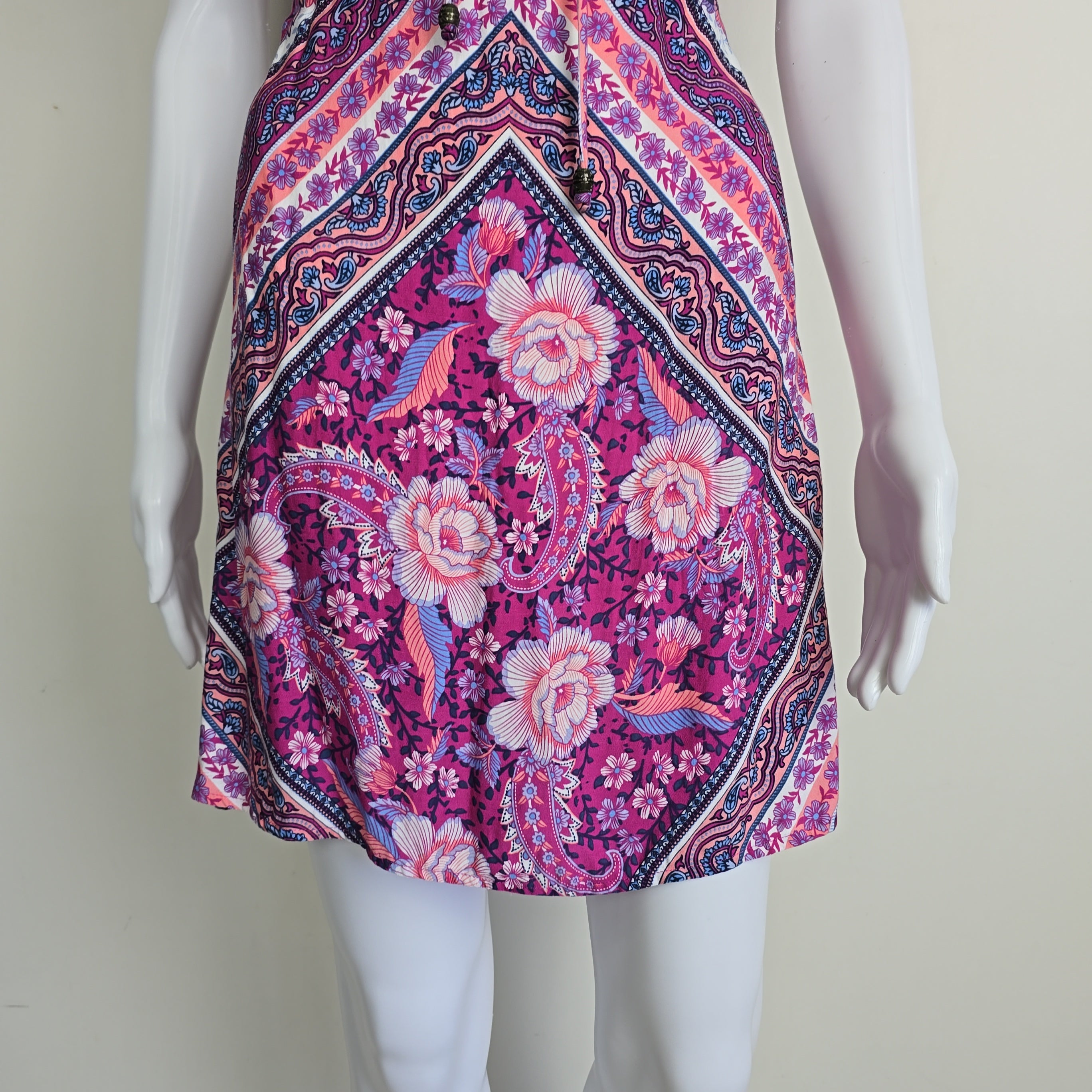 Mannequin wearing a colorful patterned garment on a plain background