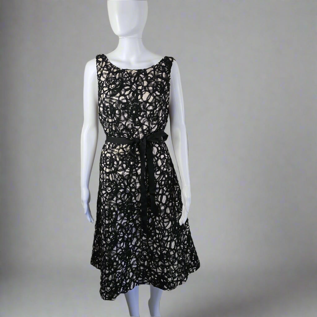 Black lace dress on a mannequin against a white wall