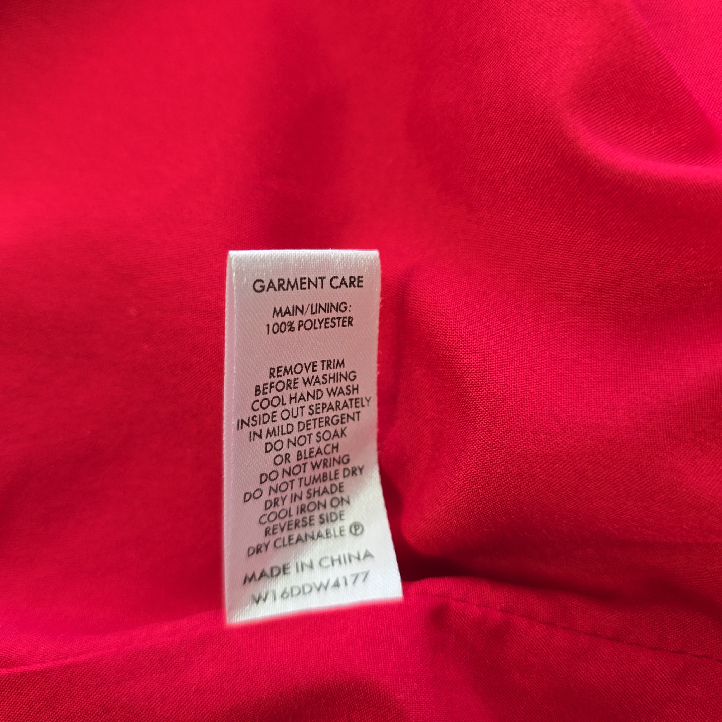 Garment care label on a red fabric background
